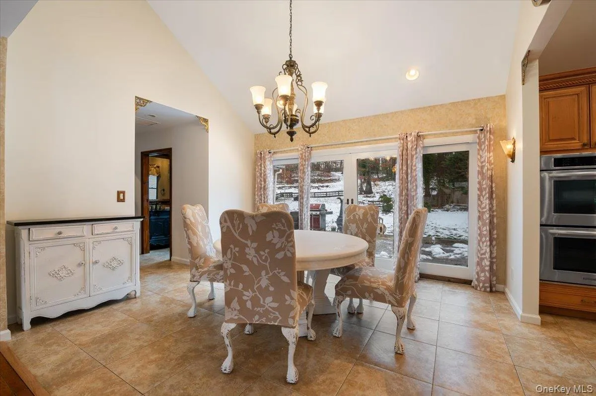 Dining area featuring light tile patterned floors, high vaulted ceiling, a chandelier, and recessed lighting Dining area featuring light tile patterned floors, high vaulted ceiling, a chandelier, and recessed lighting