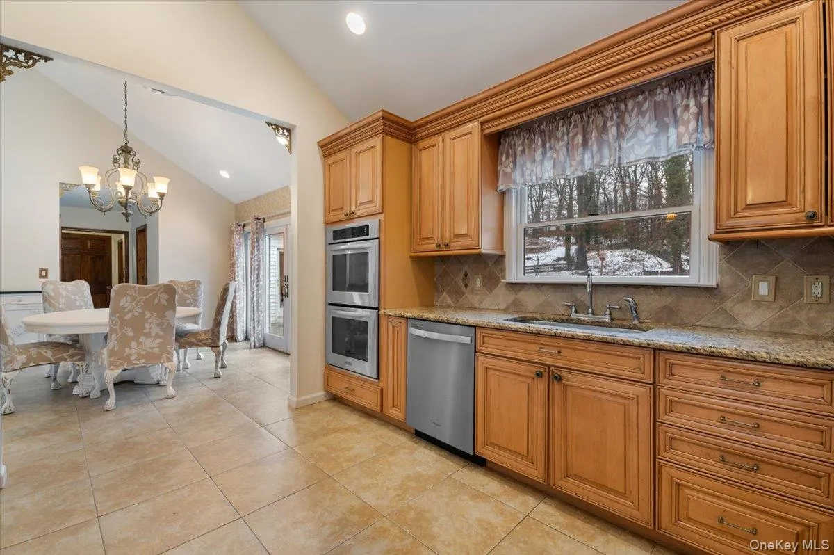 Kitchen featuring light stone countertops, appliances with stainless steel finishes, tasteful backsplash, recessed lighting, and brown cabinetry Kitchen featuring light stone countertops, appliances with stainless steel finishes, tasteful backsplash, recessed lighting, and brown cabinetry