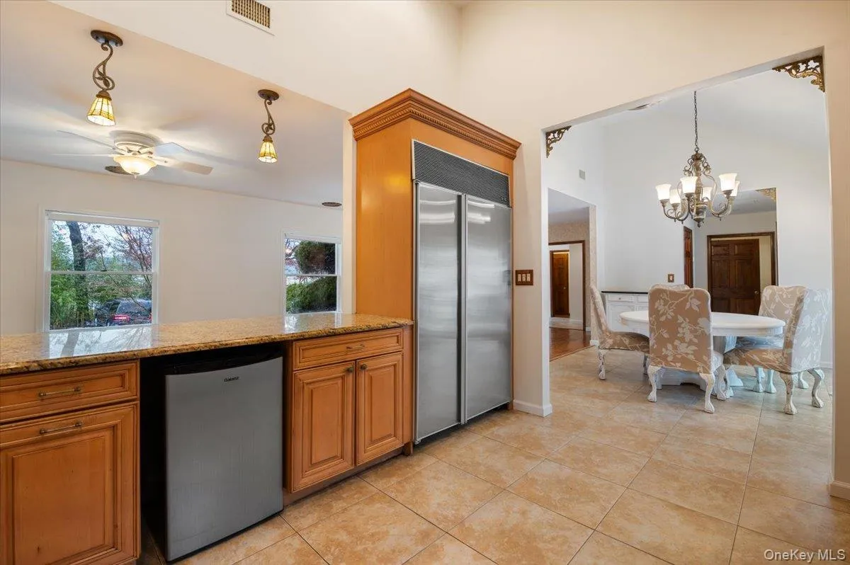 Kitchen with decorative light fixtures, stainless steel built in fridge, dishwasher, brown cabinets, and light stone countertops Kitchen with decorative light fixtures, stainless steel built in fridge, dishwasher, brown cabinets, and light stone countertops