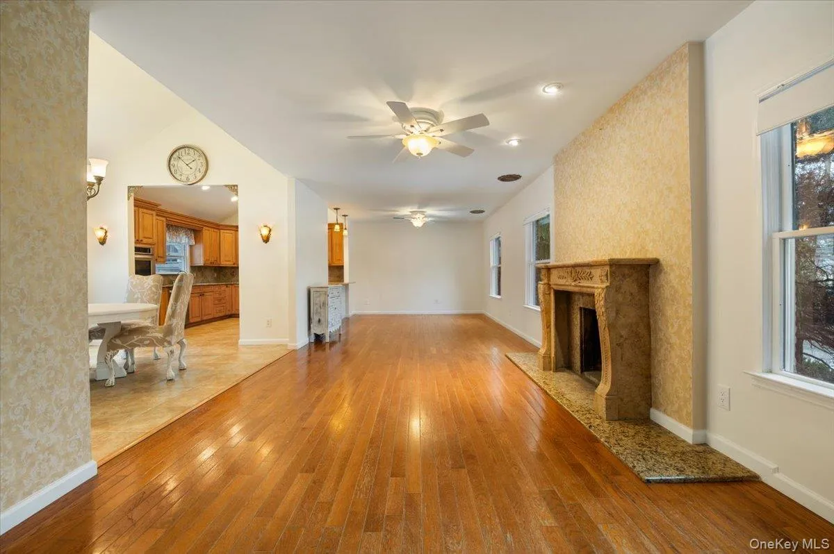 Unfurnished living room with a premium fireplace, a ceiling fan, and light wood-type flooring Unfurnished living room with a premium fireplace, a ceiling fan, and light wood-type flooring