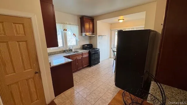 Kitchen with black appliances, under cabinet range hood, and light stone countertops Kitchen with black appliances, under cabinet range hood, and light stone countertops