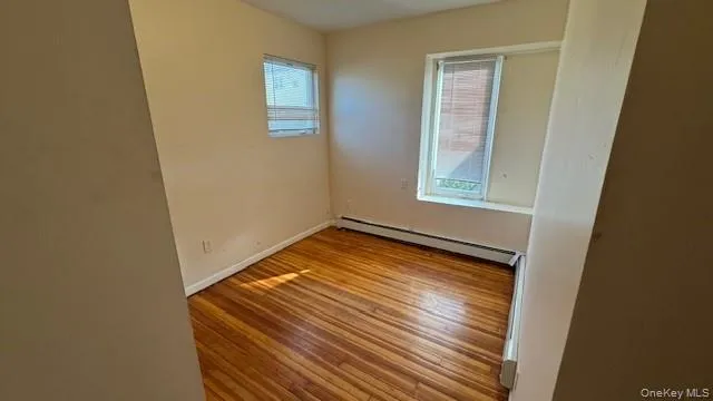 Empty room with light wood-type flooring and baseboard heating Empty room with light wood-type flooring and baseboard heating