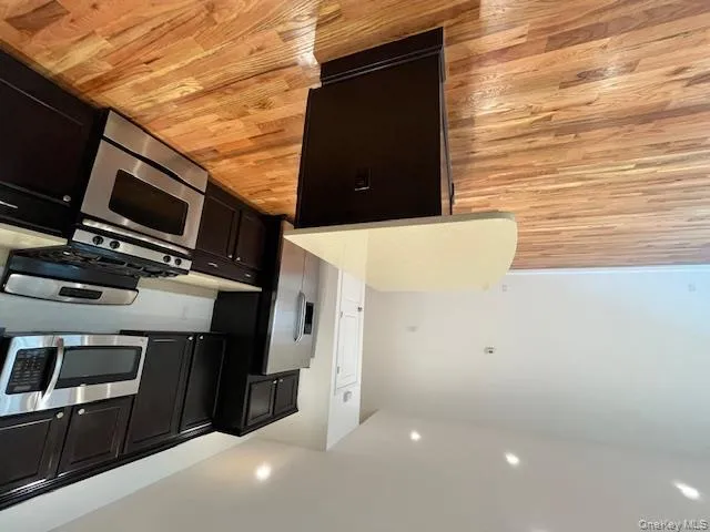 Kitchen featuring stove, a kitchen island, dark cabinetry, light wood finished floors, and recessed lighting Kitchen featuring stove, a kitchen island, dark cabinetry, light wood finished floors, and recessed lighting