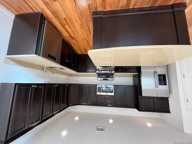 Kitchen featuring black range oven, stainless steel refrigerator, light stone countertops, dishwasher, and recessed lighting Kitchen featuring black range oven, stainless steel refrigerator, light stone countertops, dishwasher, and recessed lighting