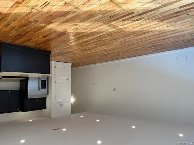 Kitchen with dark cabinets, recessed lighting, open floor plan, light countertops, and light wood-type flooring Kitchen with dark cabinets, recessed lighting, open floor plan, light countertops, and light wood-type flooring