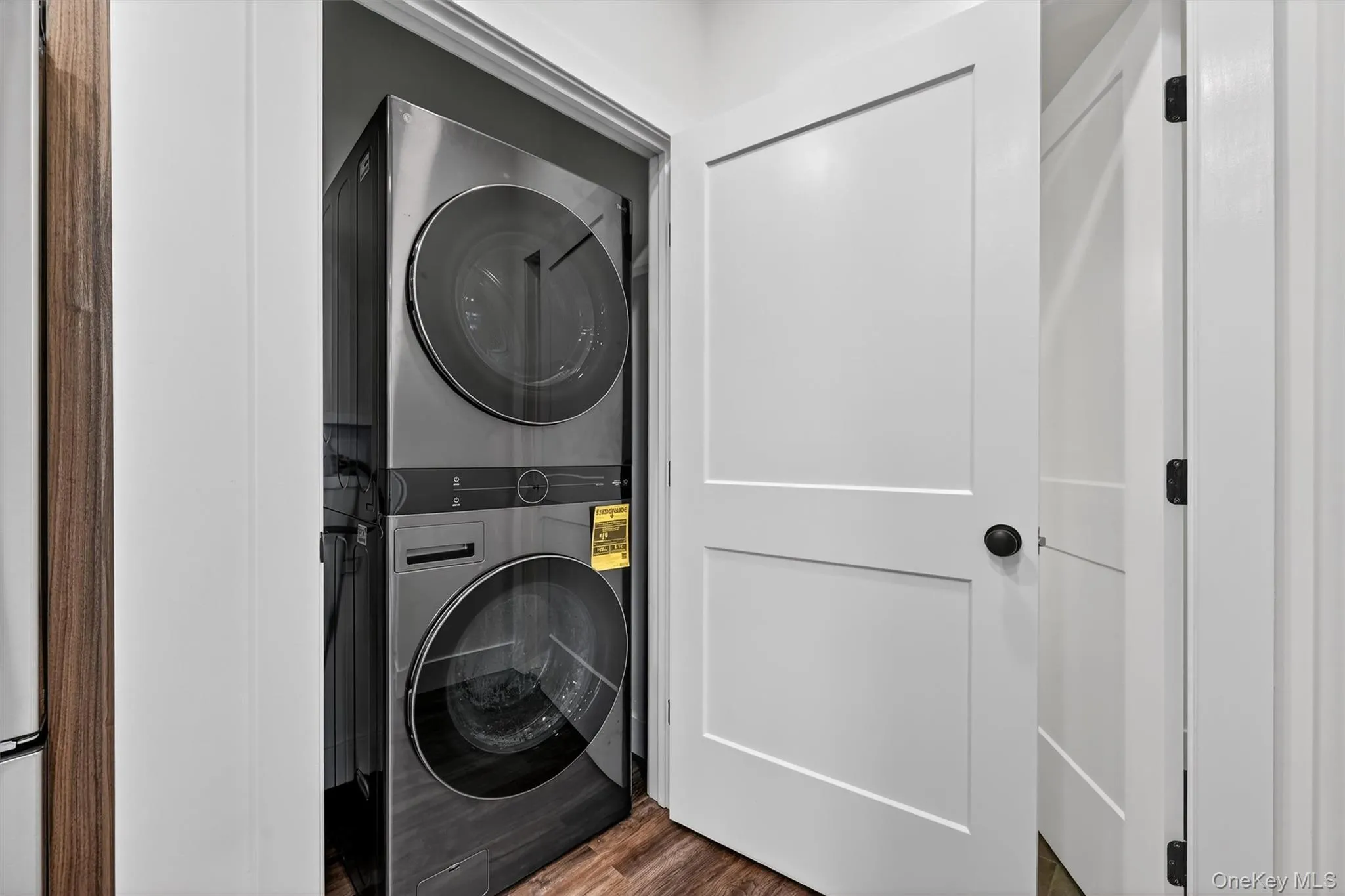 Laundry room featuring stacked washer / dryer and dark wood finished floors Laundry room featuring stacked washer / dryer and dark wood finished floors