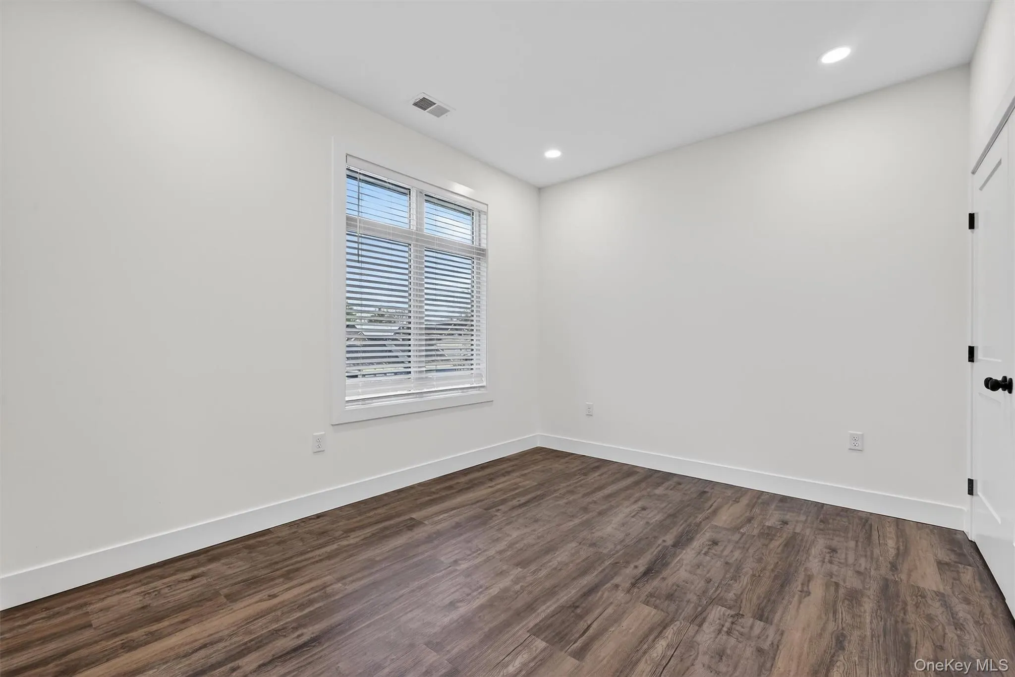 Unfurnished room with dark wood-style flooring and recessed lighting Unfurnished room with dark wood-style flooring and recessed lighting