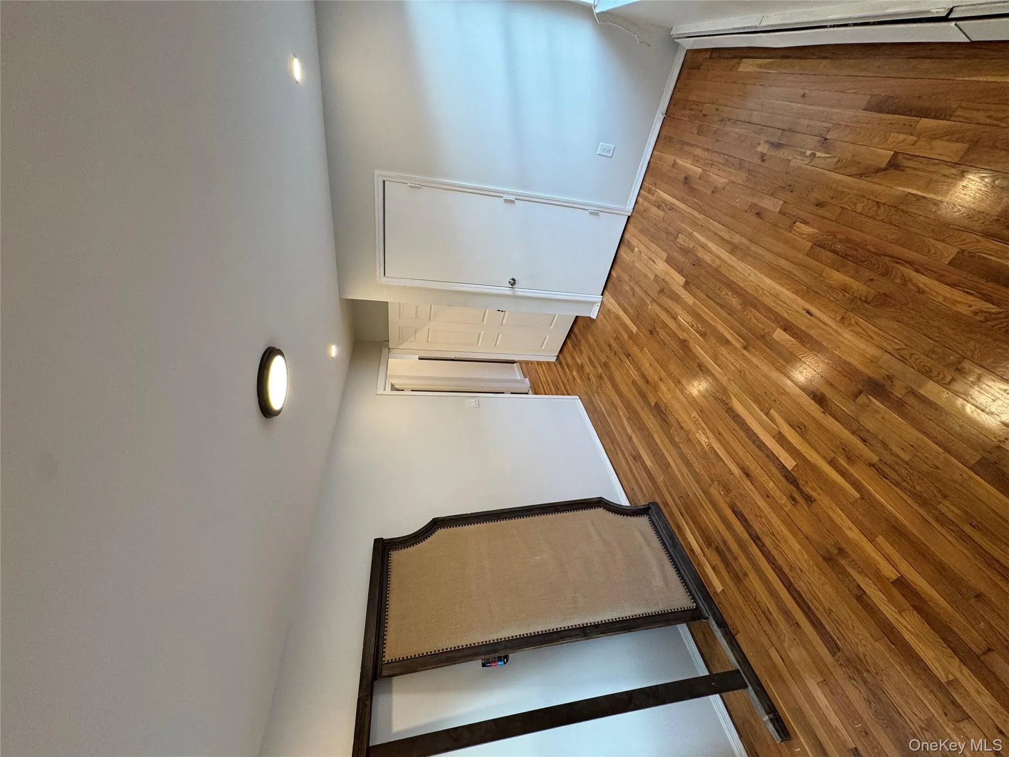 Unfurnished bedroom featuring hardwood / wood-style flooring and baseboard heating Unfurnished bedroom featuring hardwood / wood-style flooring and baseboard heating