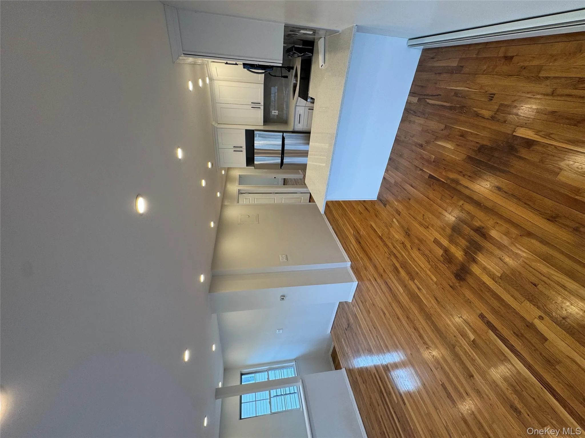 Kitchen with white cabinetry, recessed lighting, open floor plan, baseboard heating, and refrigerator Kitchen with white cabinetry, recessed lighting, open floor plan, baseboard heating, and refrigerator