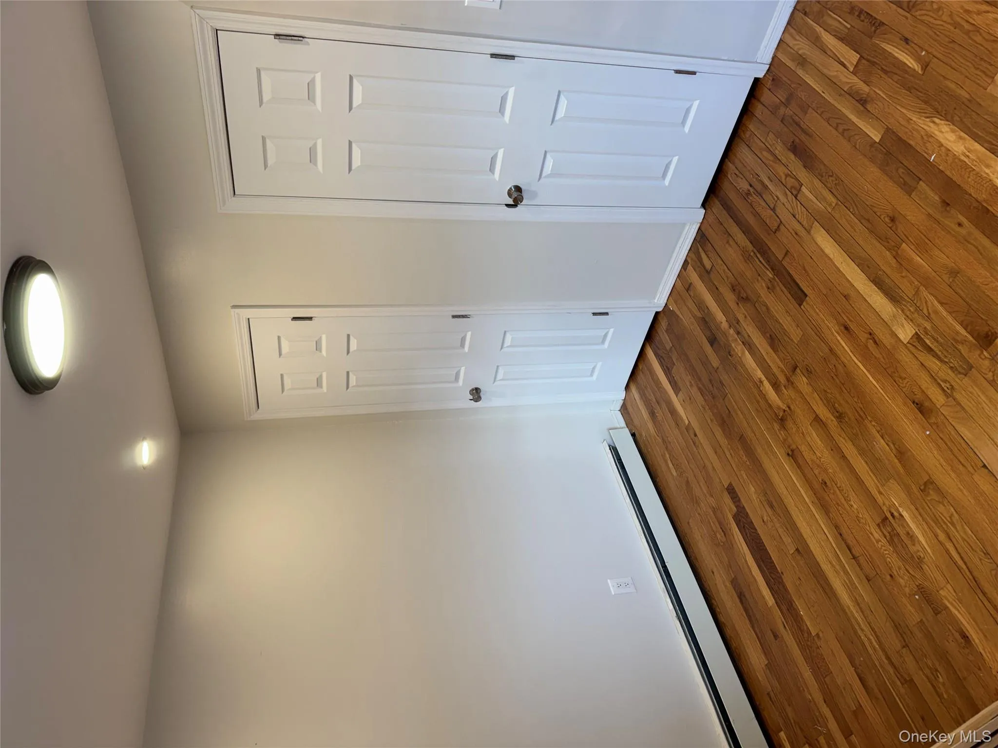 Unfurnished bedroom featuring a baseboard radiator and dark wood-style flooring Unfurnished bedroom featuring a baseboard radiator and dark wood-style flooring