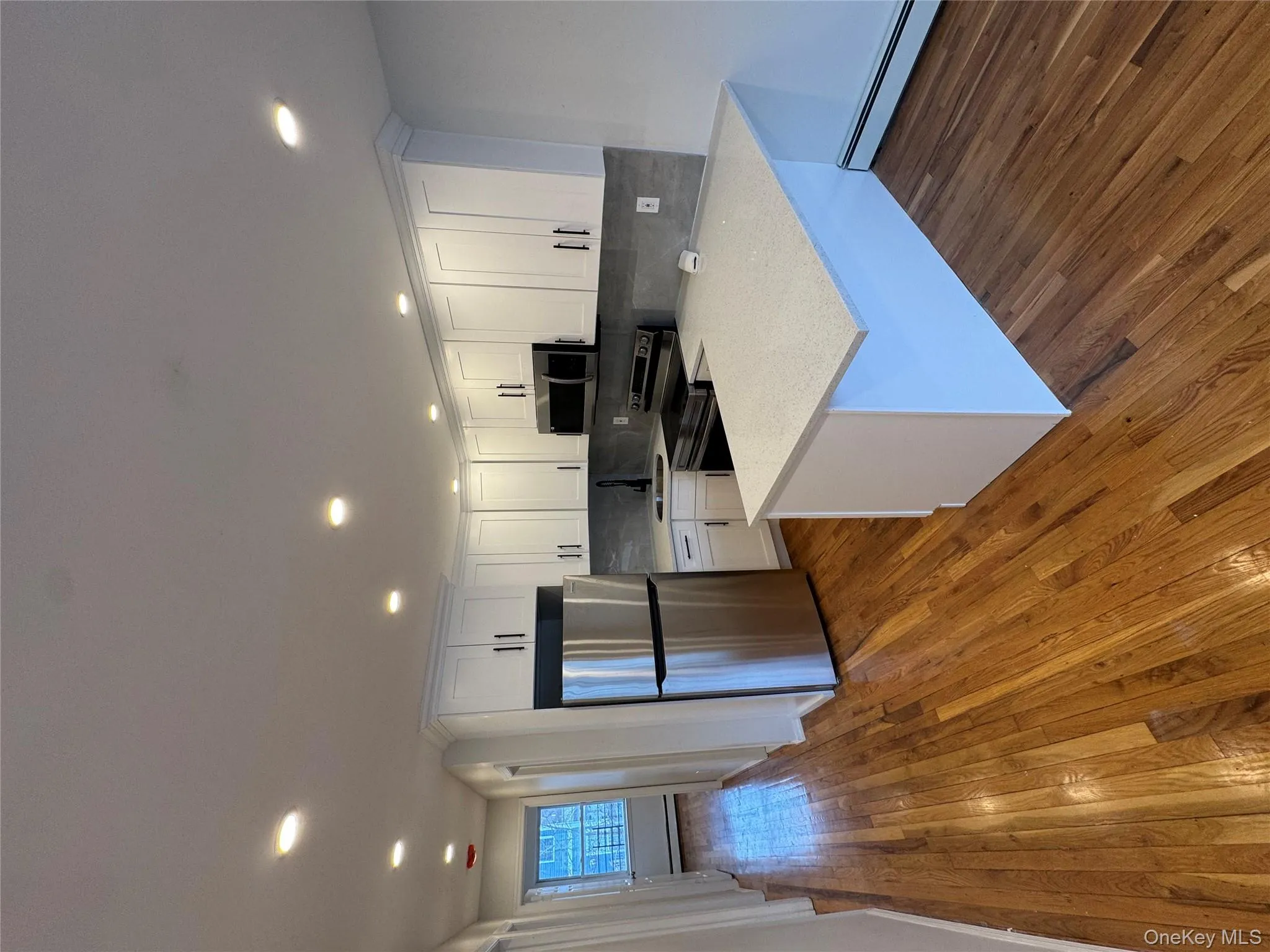 Kitchen featuring a peninsula, stainless steel appliances, white cabinetry, tasteful backsplash, and a baseboard heating unit Kitchen featuring a peninsula, stainless steel appliances, white cabinetry, tasteful backsplash, and a baseboard heating unit