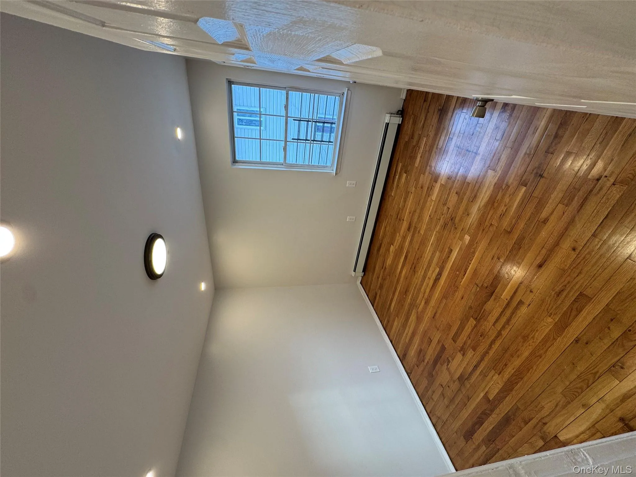 Empty room with hardwood / wood-style flooring, a baseboard radiator, and recessed lighting Empty room with hardwood / wood-style flooring, a baseboard radiator, and recessed lighting