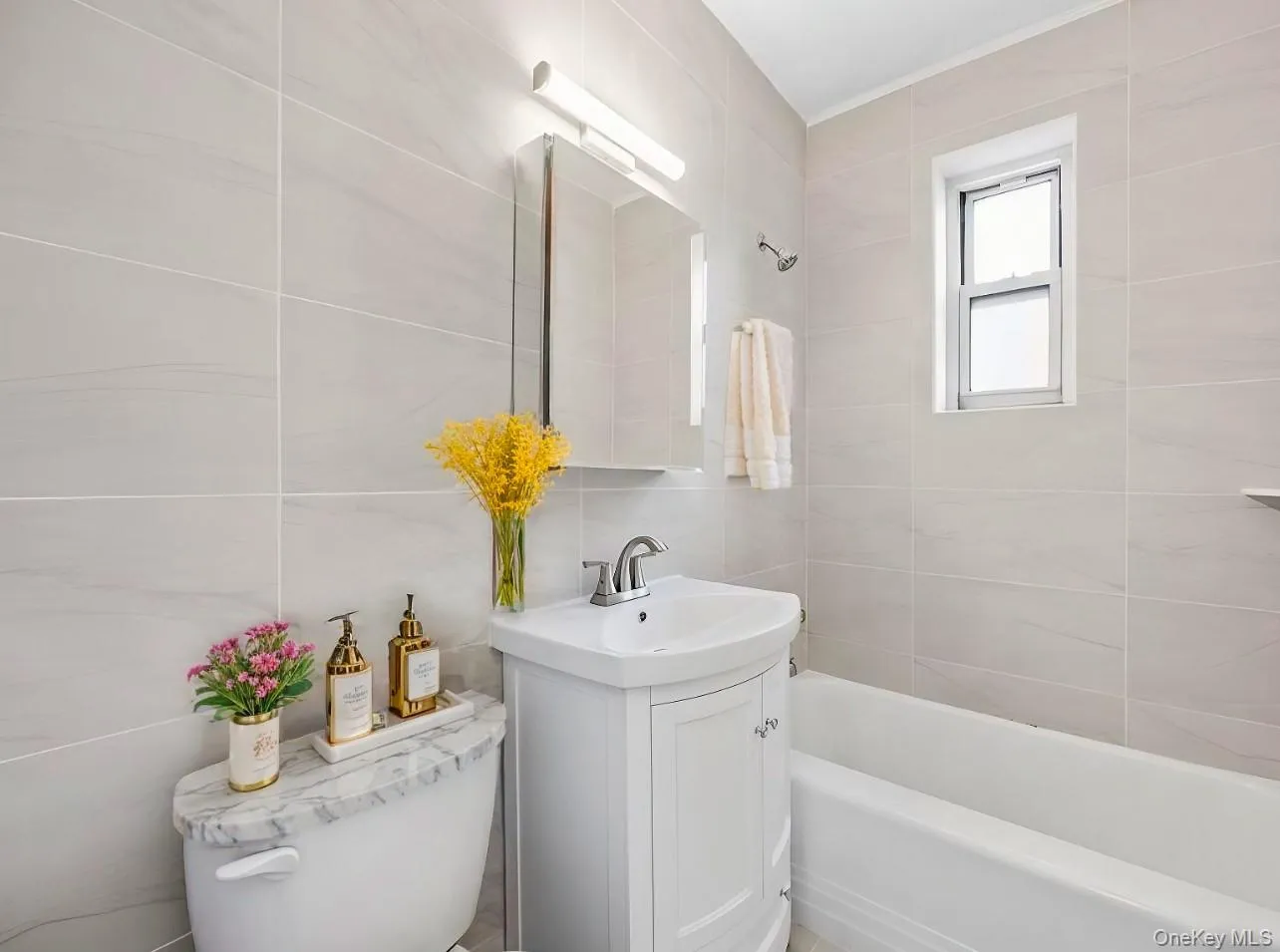 Bathroom with tile walls, vanity, and shower / washtub combination Bathroom with tile walls, vanity, and shower / washtub combination