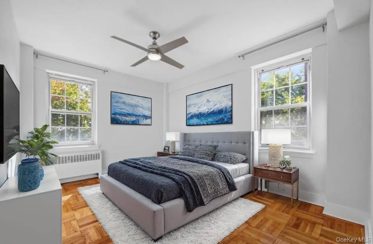Bedroom featuring multiple windows, ceiling fan, and radiator Bedroom featuring multiple windows, ceiling fan, and radiator