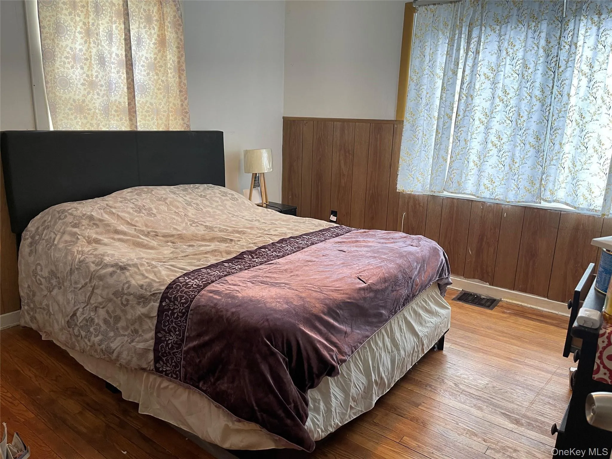 Bedroom with wood walls, a wainscoted wall, and wood-type flooring Bedroom with wood walls, a wainscoted wall, and wood-type flooring