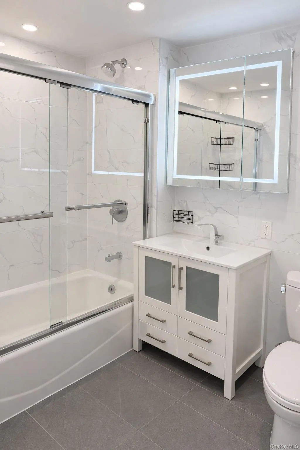 Bathroom featuring tile walls, combined bath / shower with glass door, vanity, dark tile patterned flooring, and recessed lighting Bathroom featuring tile walls, combined bath / shower with glass door, vanity, dark tile patterned flooring, and recessed lighting