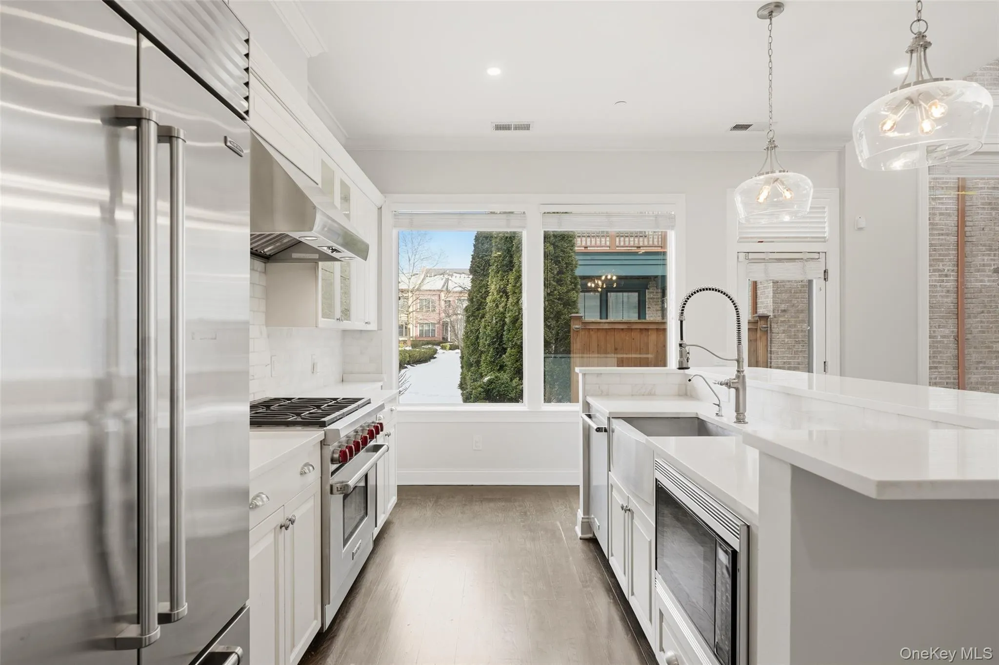 Kitchen featuring built in appliances, glass insert cabinets, white cabinets, pendant lighting, and crown molding Kitchen featuring built in appliances, glass insert cabinets, white cabinets, pendant lighting, and crown molding