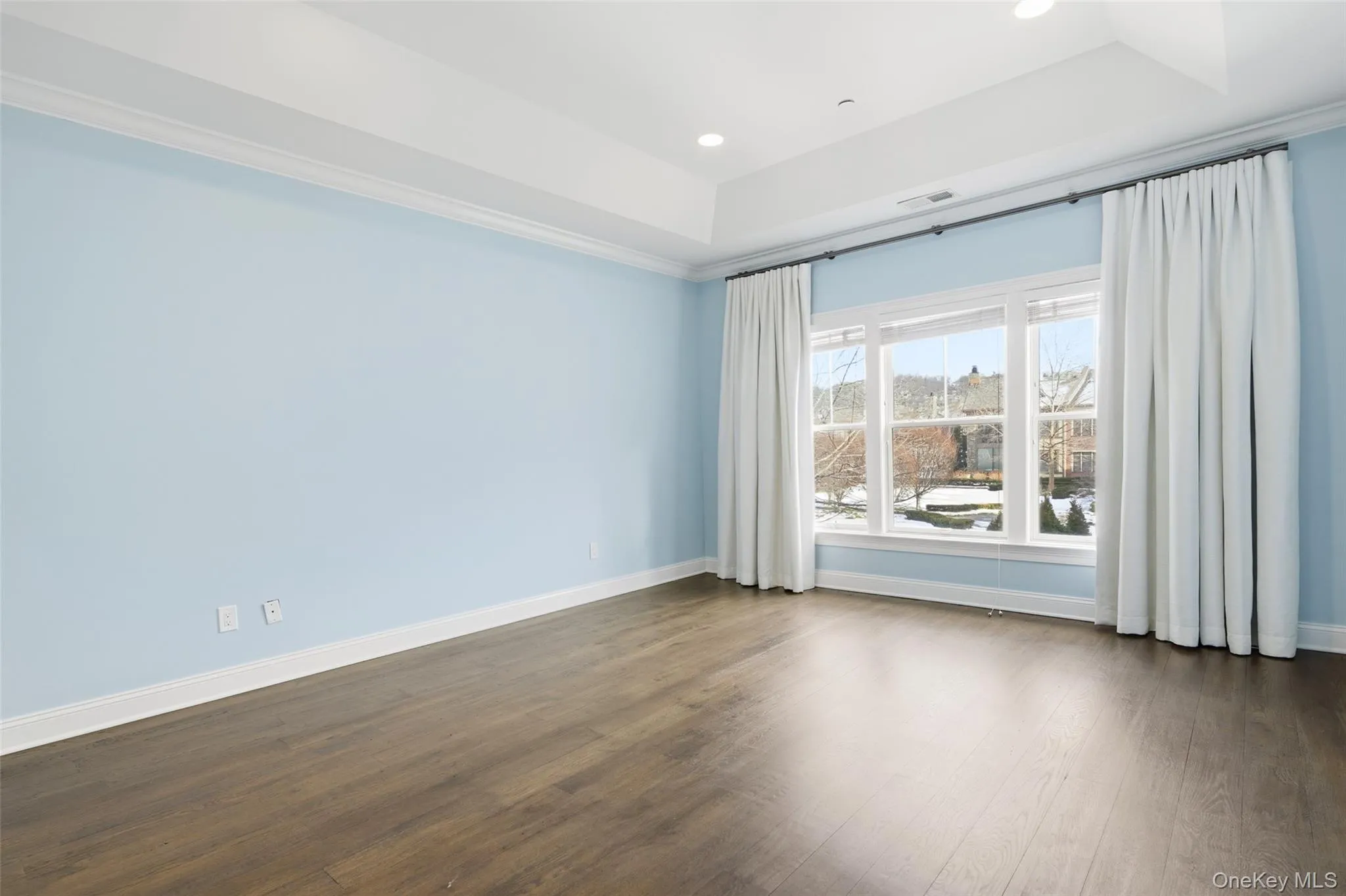 Empty room featuring a raised ceiling, dark wood-style floors, and recessed lighting Empty room featuring a raised ceiling, dark wood-style floors, and recessed lighting