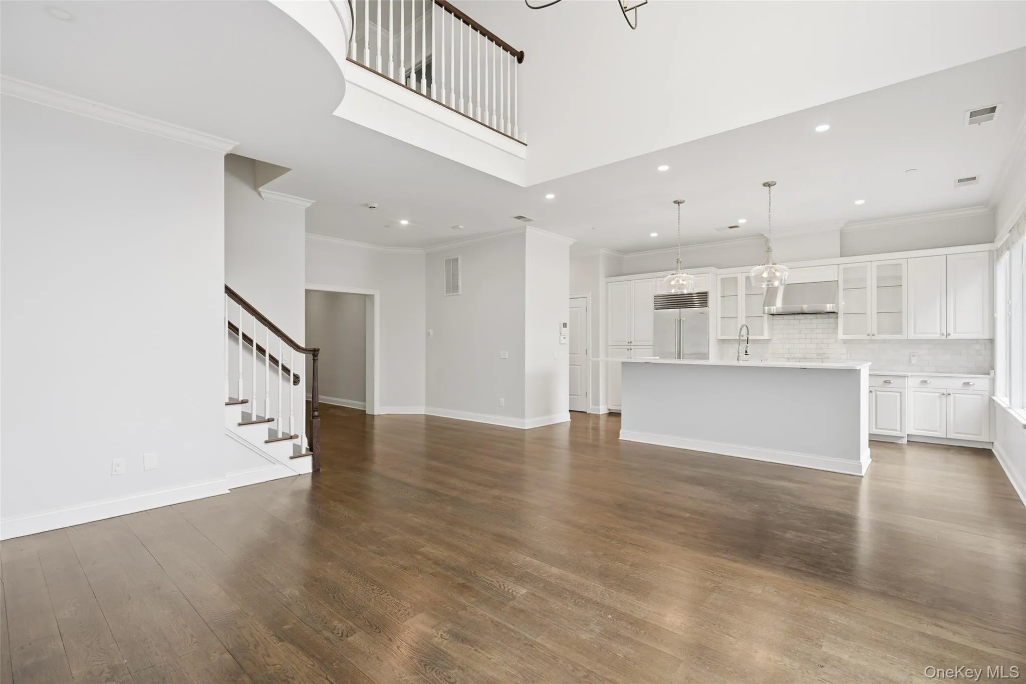 Unfurnished living room with ornamental molding, stairway, dark wood-style floors, recessed lighting, and a chandelier Unfurnished living room with ornamental molding, stairway, dark wood-style floors, recessed lighting, and a chandelier