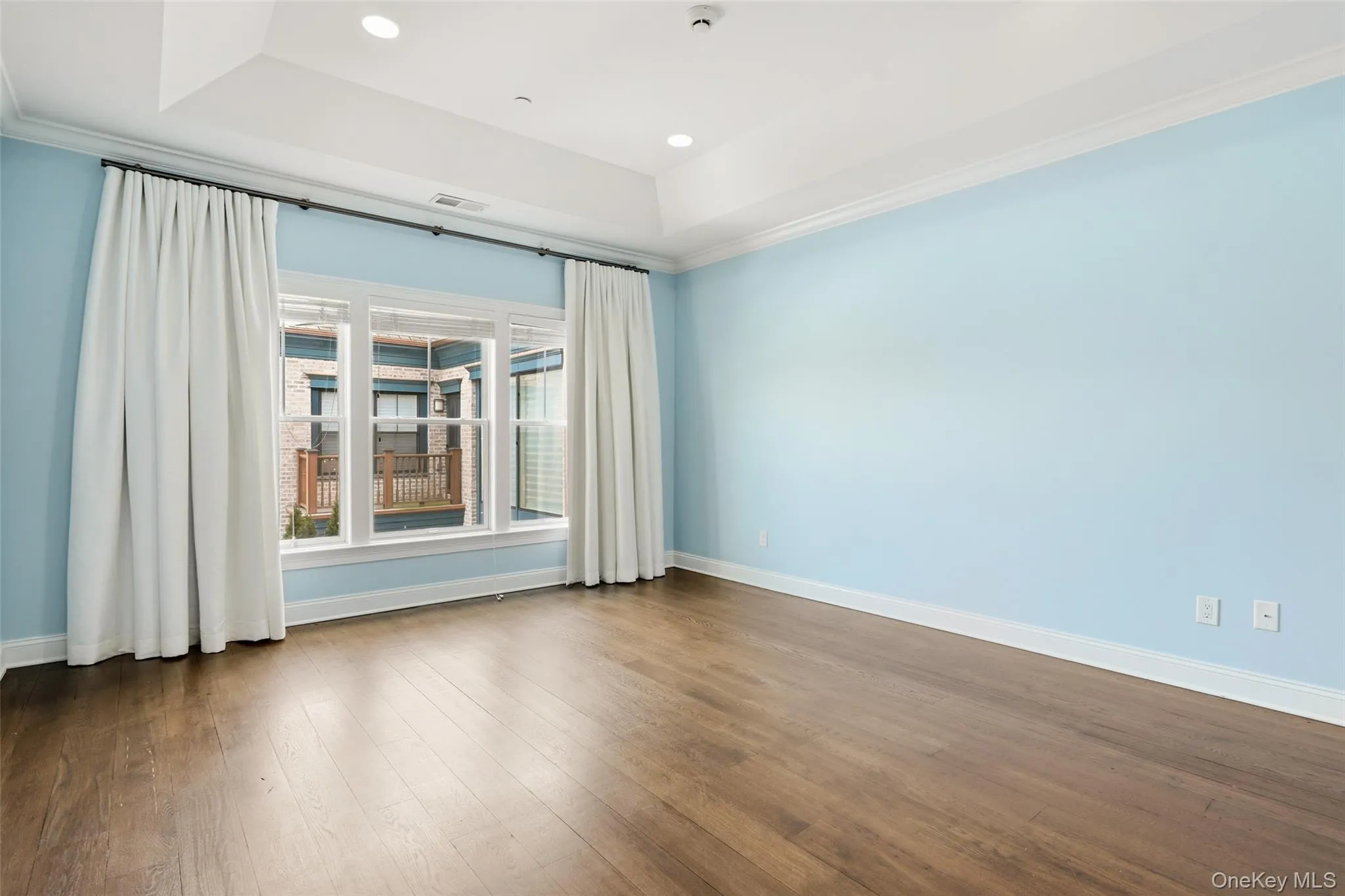 Unfurnished room with crown molding, a tray ceiling, dark wood-style floors, and recessed lighting Unfurnished room with crown molding, a tray ceiling, dark wood-style floors, and recessed lighting