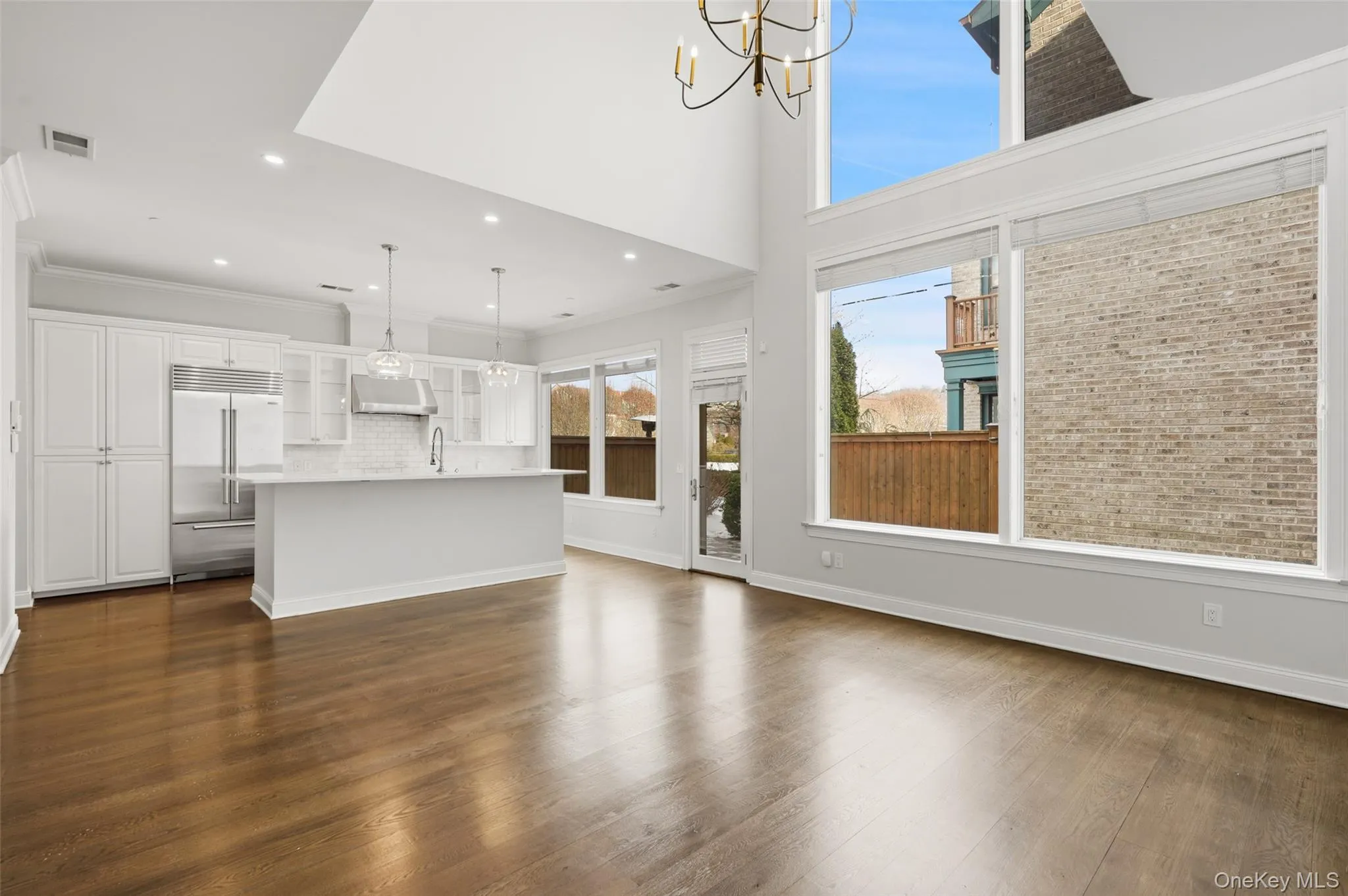 Unfurnished living room with dark wood-type flooring, a chandelier, recessed lighting, a high ceiling, and ornamental molding Unfurnished living room with dark wood-type flooring, a chandelier, recessed lighting, a high ceiling, and ornamental molding