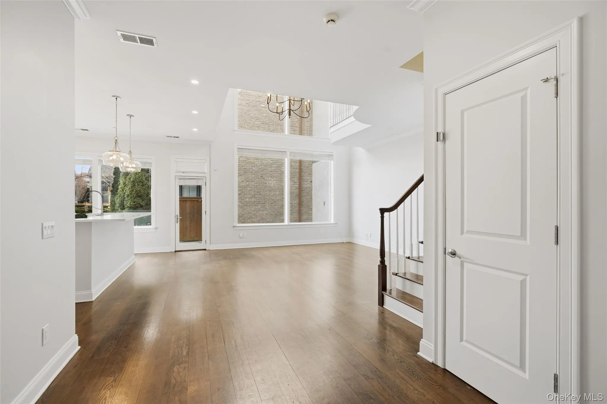 Unfurnished living room with a chandelier, dark wood-style flooring, recessed lighting, stairway, and ornamental molding Unfurnished living room with a chandelier, dark wood-style flooring, recessed lighting, stairway, and ornamental molding