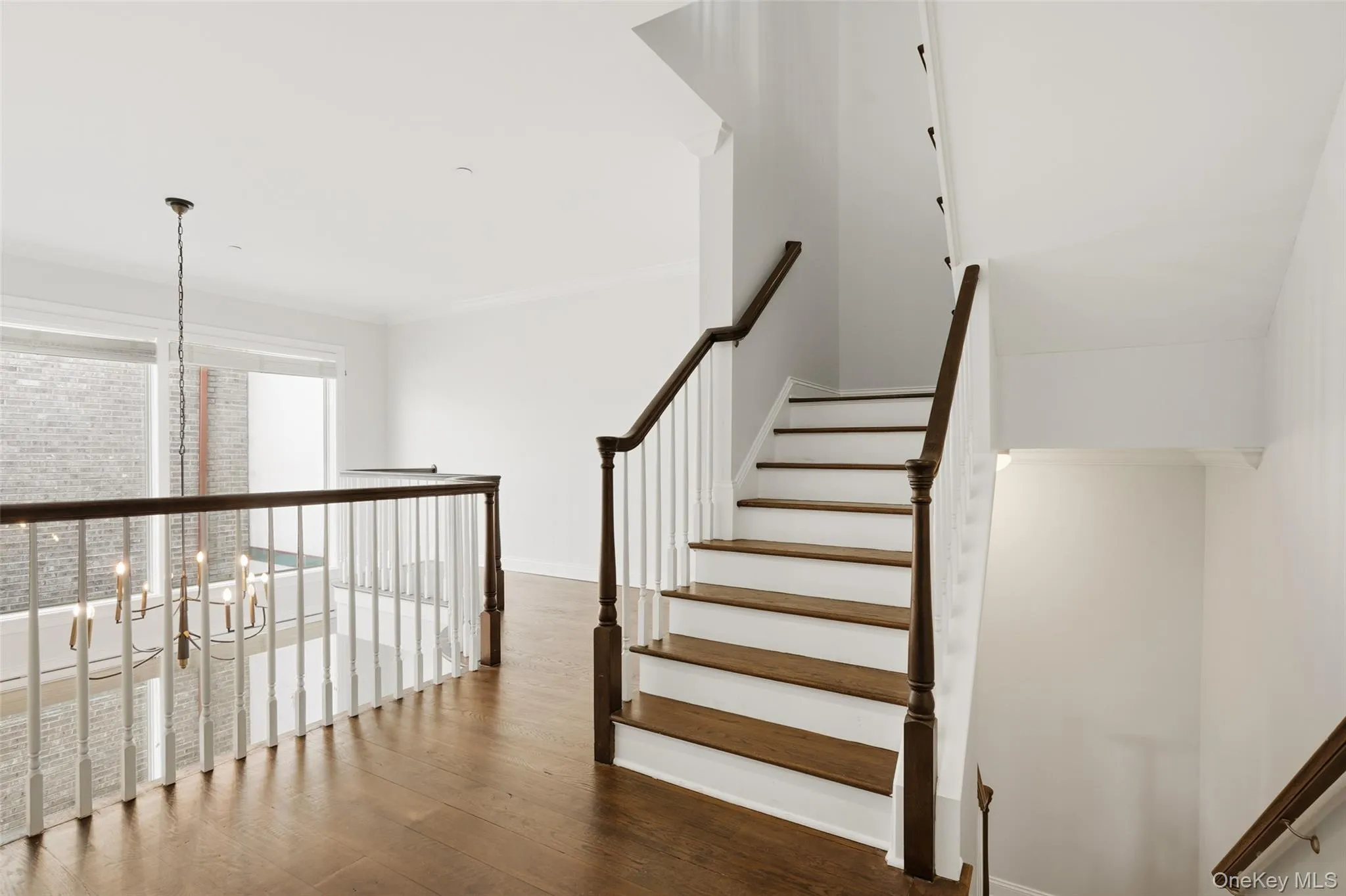 Stairway with a chandelier, hardwood / wood-style flooring, and ornamental molding Stairway with a chandelier, hardwood / wood-style flooring, and ornamental molding