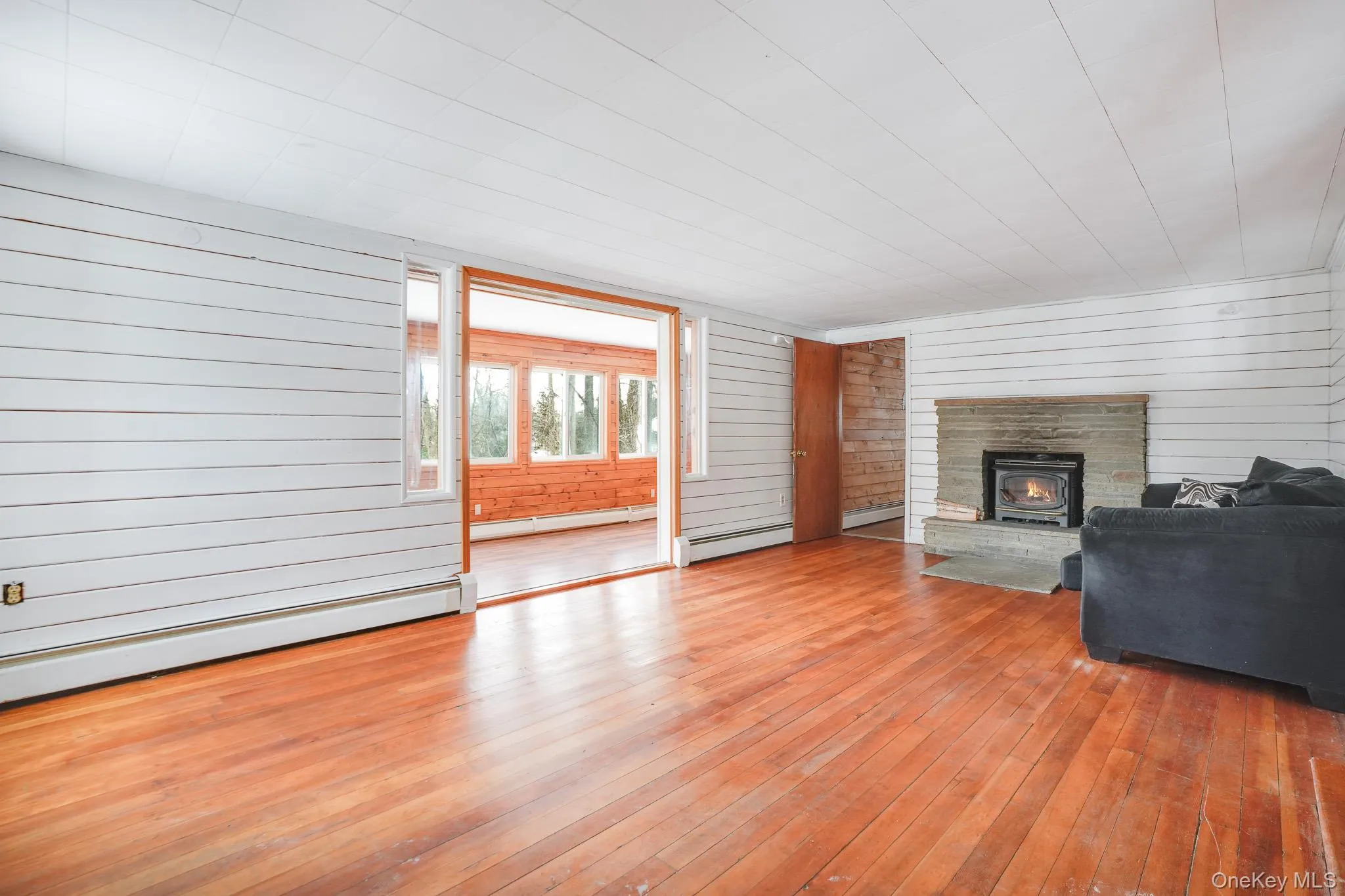 Living area with wooden walls, hardwood / wood-style floors, and baseboard heating Living area with wooden walls, hardwood / wood-style floors, and baseboard heating