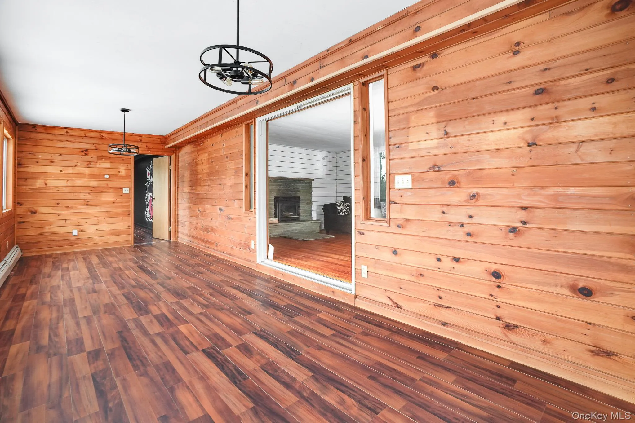 Spare room with wood walls, wood finished floors, and a fireplace with raised hearth Spare room with wood walls, wood finished floors, and a fireplace with raised hearth