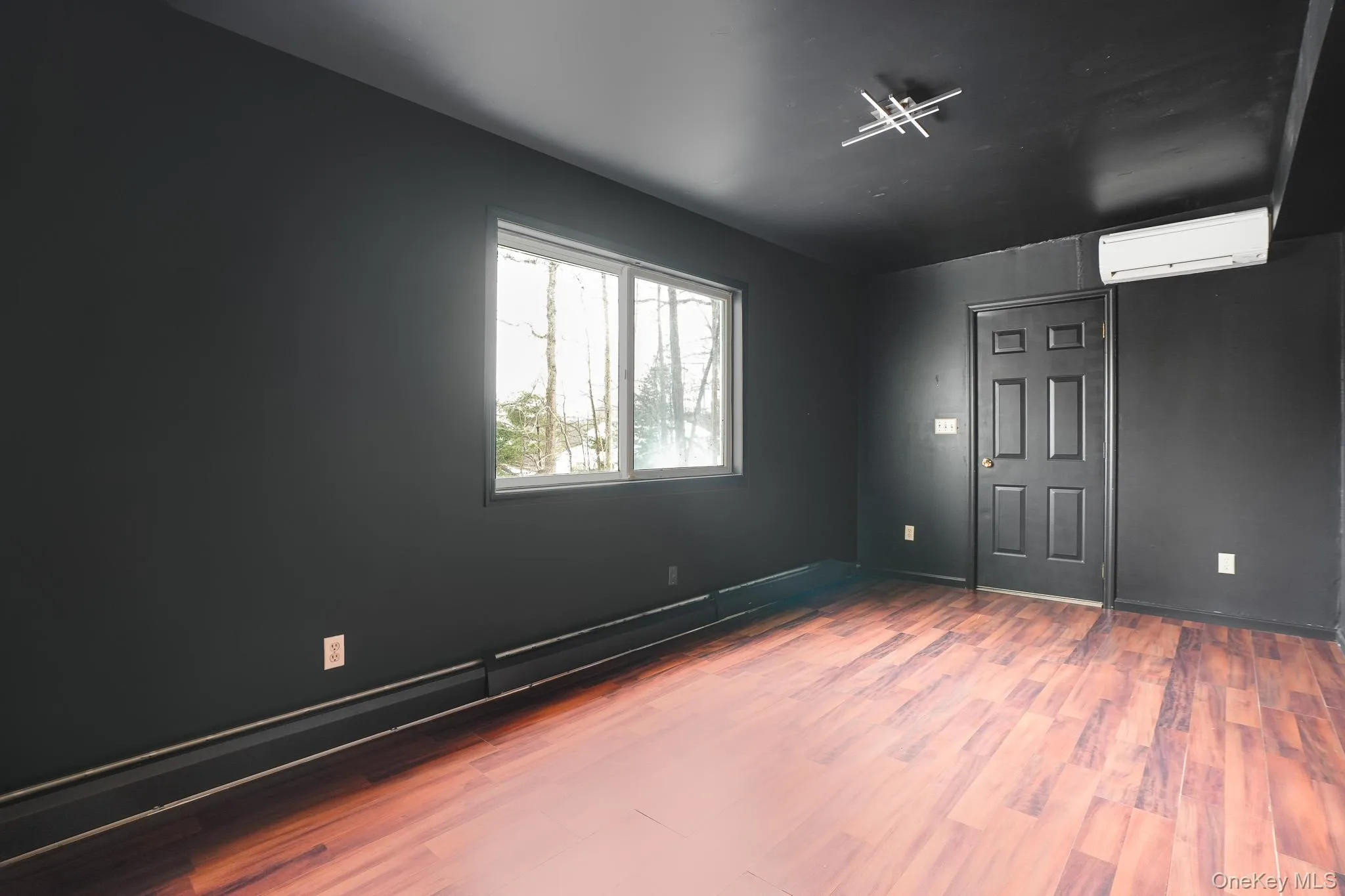 Spare room featuring wood finished floors and a wall unit AC Spare room featuring wood finished floors and a wall unit AC