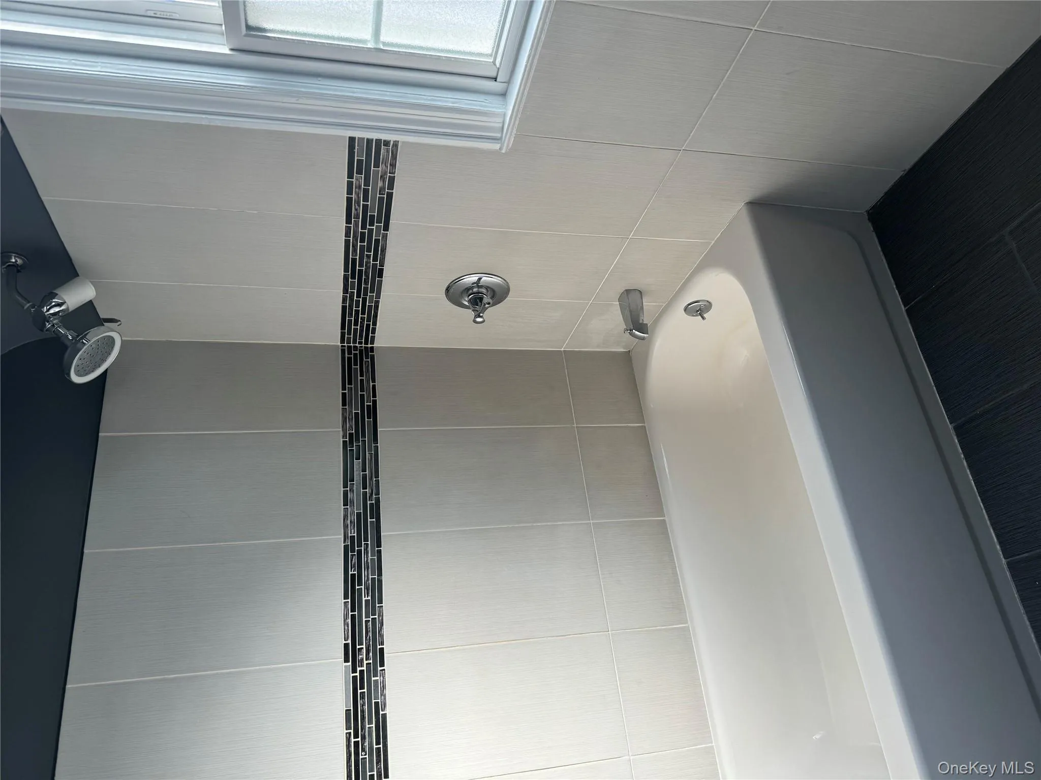 Full bath featuring washtub / shower combination, tile walls, and tile patterned flooring Full bath featuring washtub / shower combination, tile walls, and tile patterned flooring
