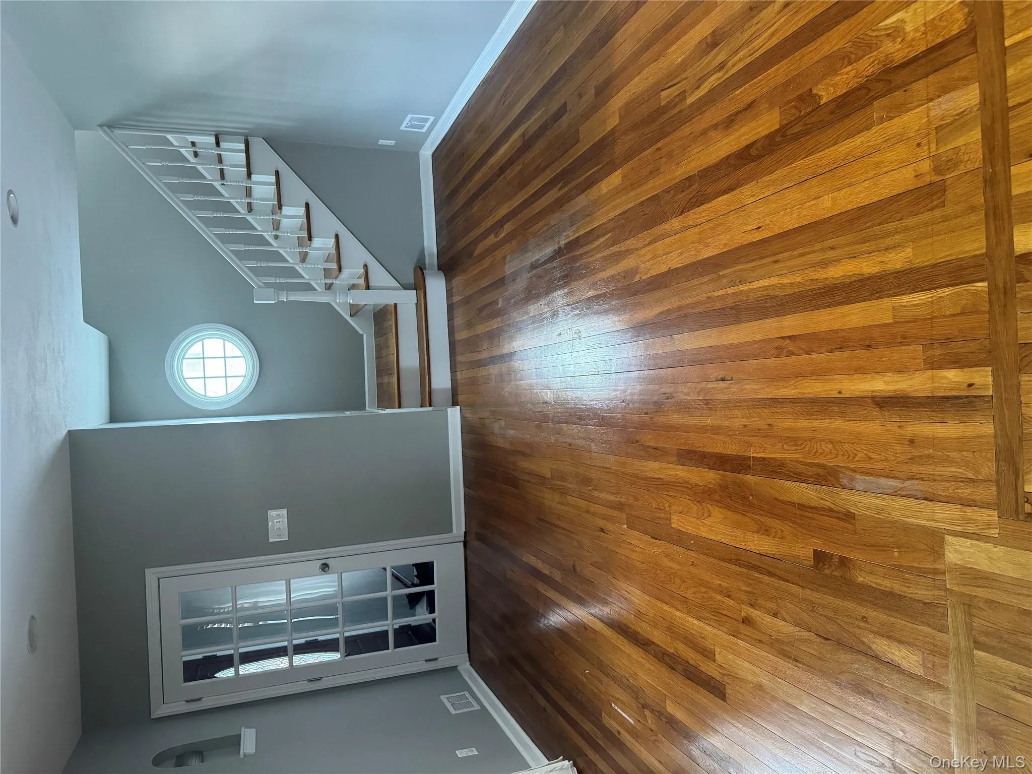 Unfurnished living room featuring stairs and dark wood-type flooring Unfurnished living room featuring stairs and dark wood-type flooring
