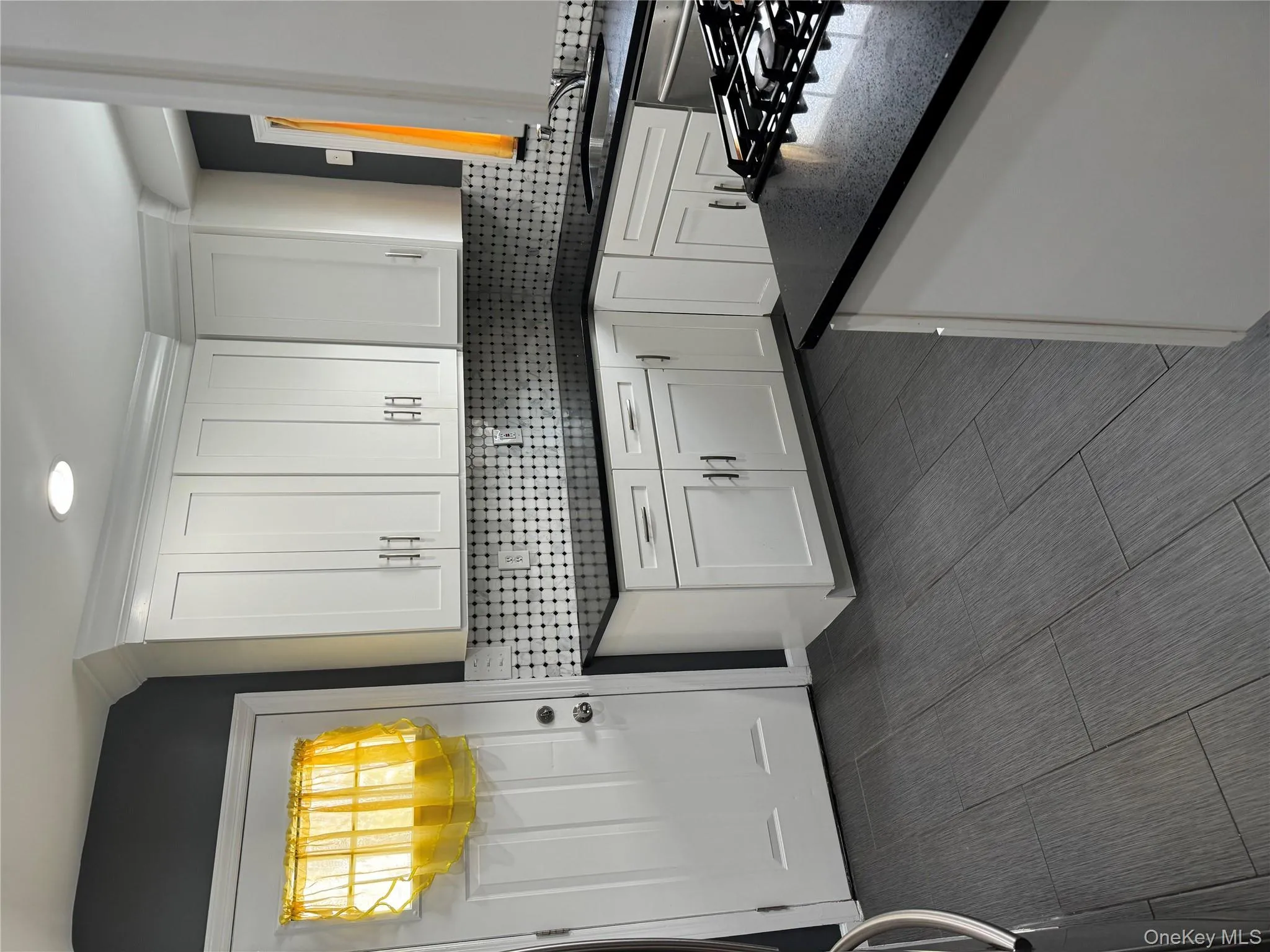 Kitchen with white cabinetry, dark stone counters, and backsplash Kitchen with white cabinetry, dark stone counters, and backsplash