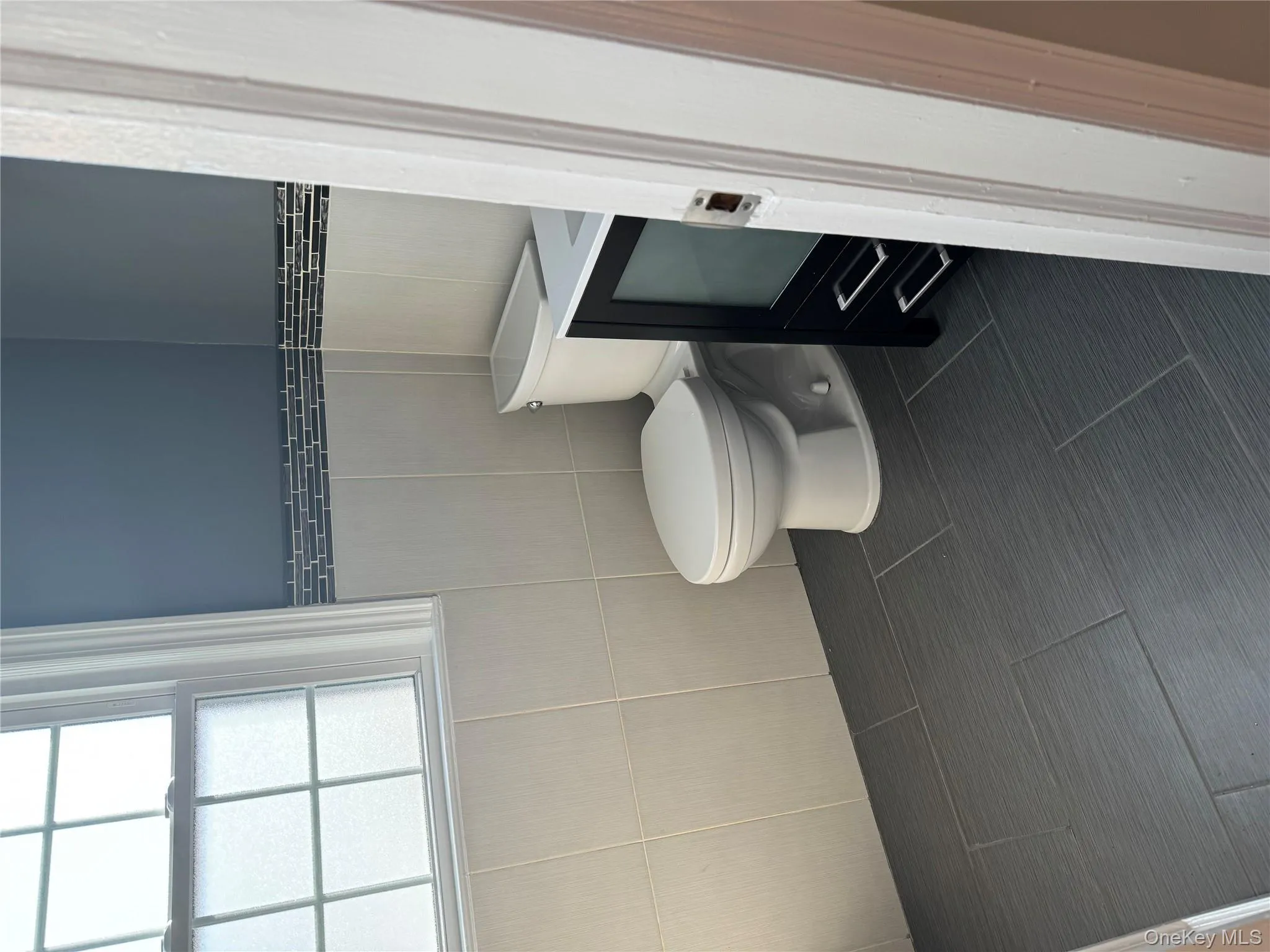 Bathroom featuring dark tile patterned flooring, vanity, and tile walls Bathroom featuring dark tile patterned flooring, vanity, and tile walls