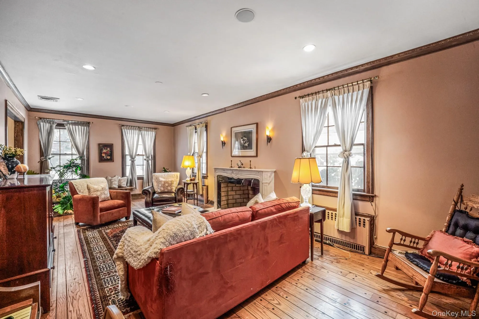 Living area with hardwood / wood-style flooring, radiator heating unit, a fireplace, ornamental molding, and recessed lighting Living area with hardwood / wood-style flooring, radiator heating unit, a fireplace, ornamental molding, and recessed lighting