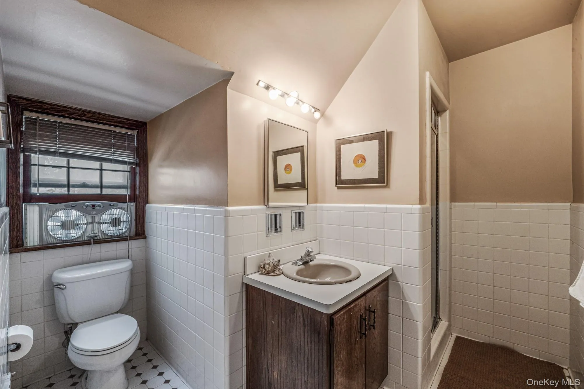 Full bath featuring vanity, tile walls, wainscoting, a shower stall, and tile patterned floors Full bath featuring vanity, tile walls, wainscoting, a shower stall, and tile patterned floors