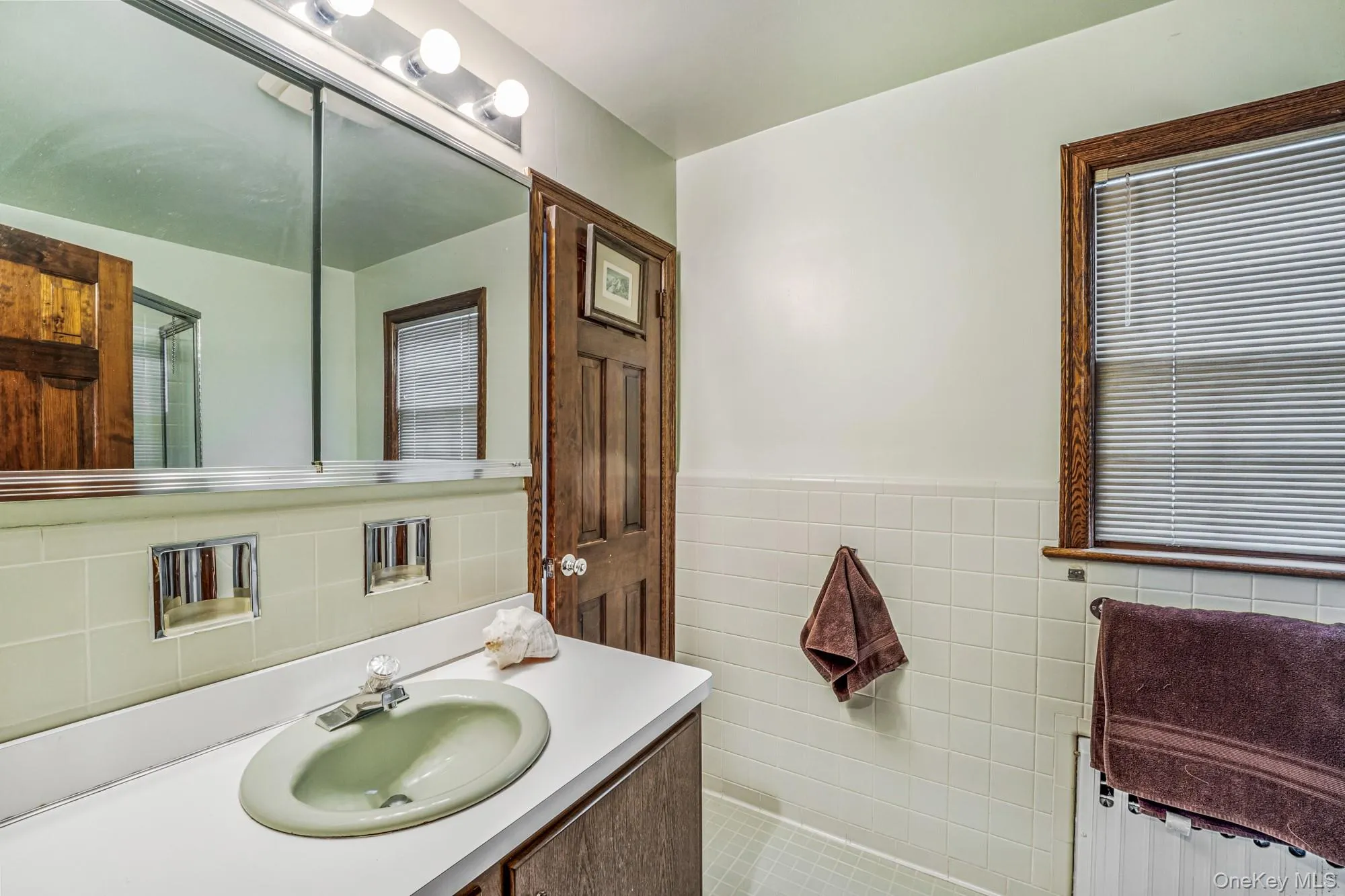 Bathroom featuring vanity, wainscoting, radiator, tile walls, and tile patterned floors Bathroom featuring vanity, wainscoting, radiator, tile walls, and tile patterned floors