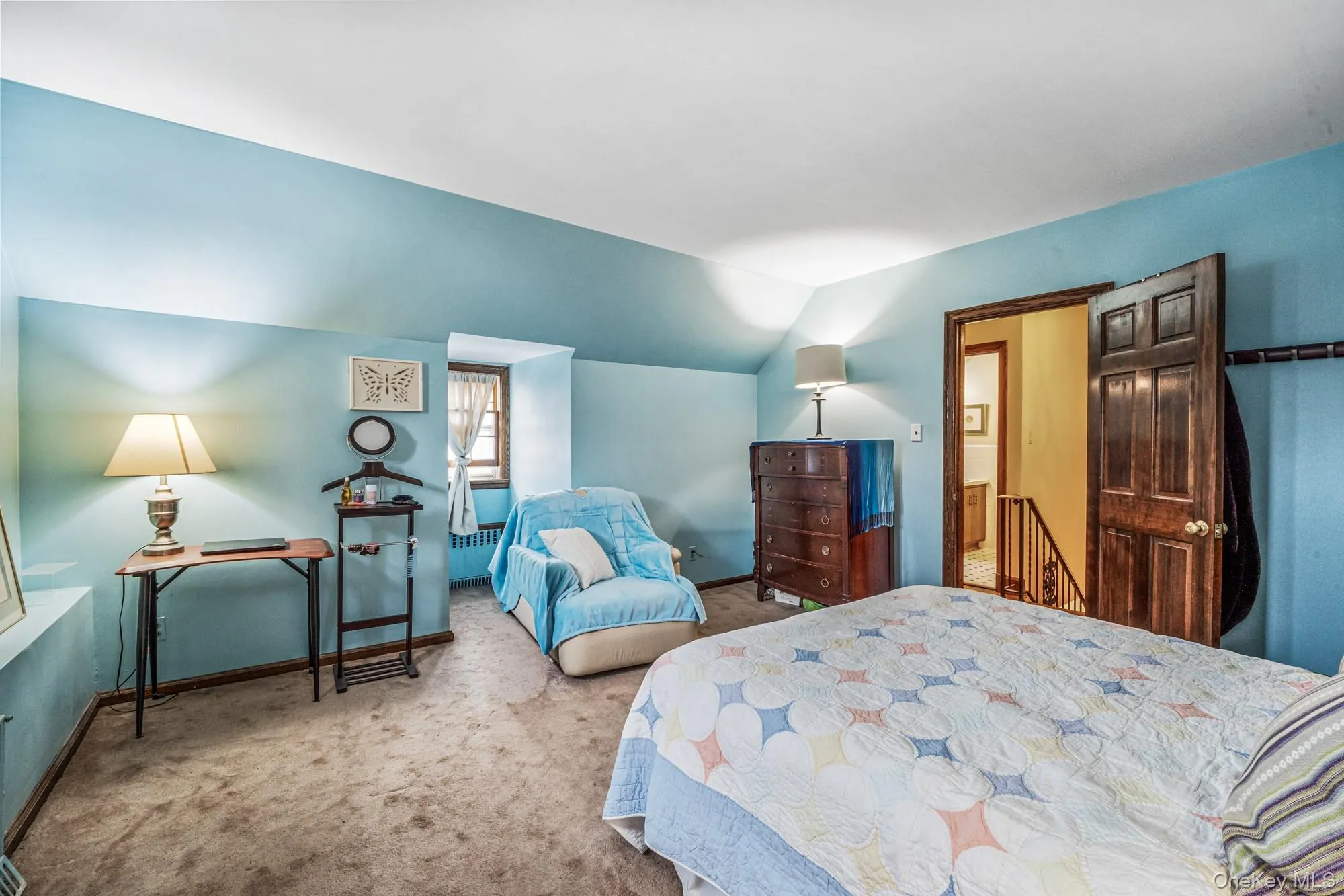 Carpeted bedroom with vaulted ceiling and radiator Carpeted bedroom with vaulted ceiling and radiator