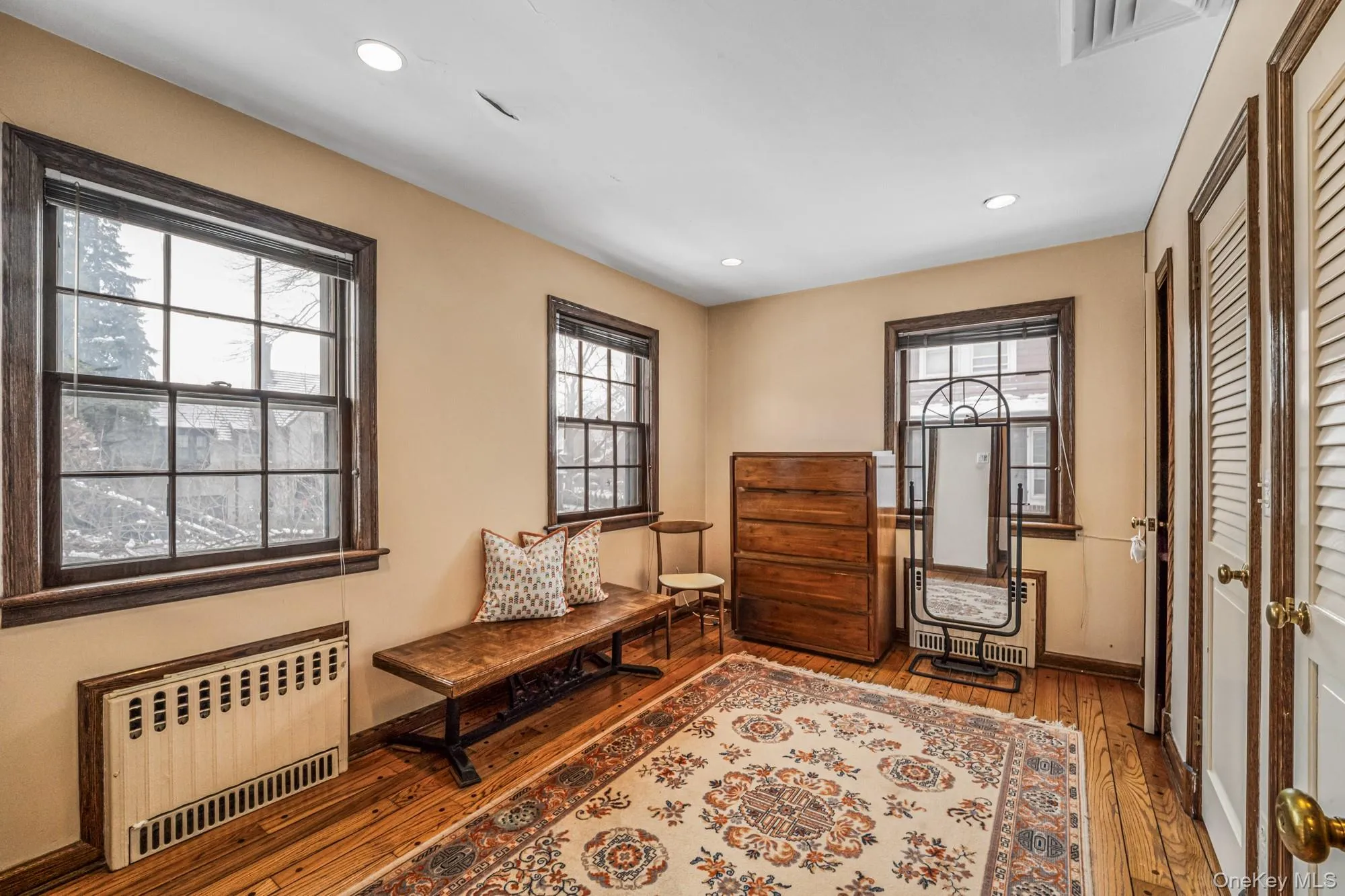 Living area featuring radiator, light wood-style flooring, healthy amount of natural light, and recessed lighting Living area featuring radiator, light wood-style flooring, healthy amount of natural light, and recessed lighting