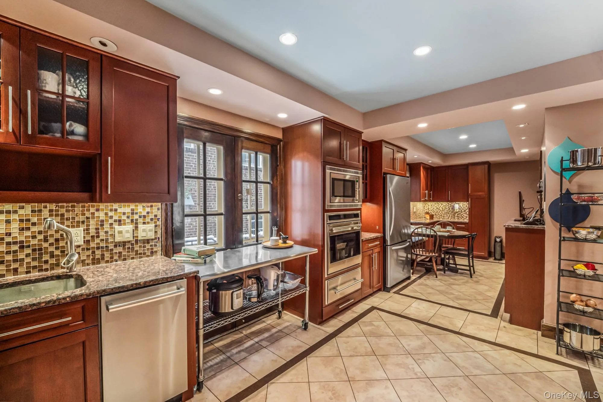 Kitchen featuring inlaid floor details, stainless steel appliances, glass insert cabinets, light stone counters, and recessed lighting Kitchen featuring inlaid floor details, stainless steel appliances, glass insert cabinets, light stone counters, and recessed lighting
