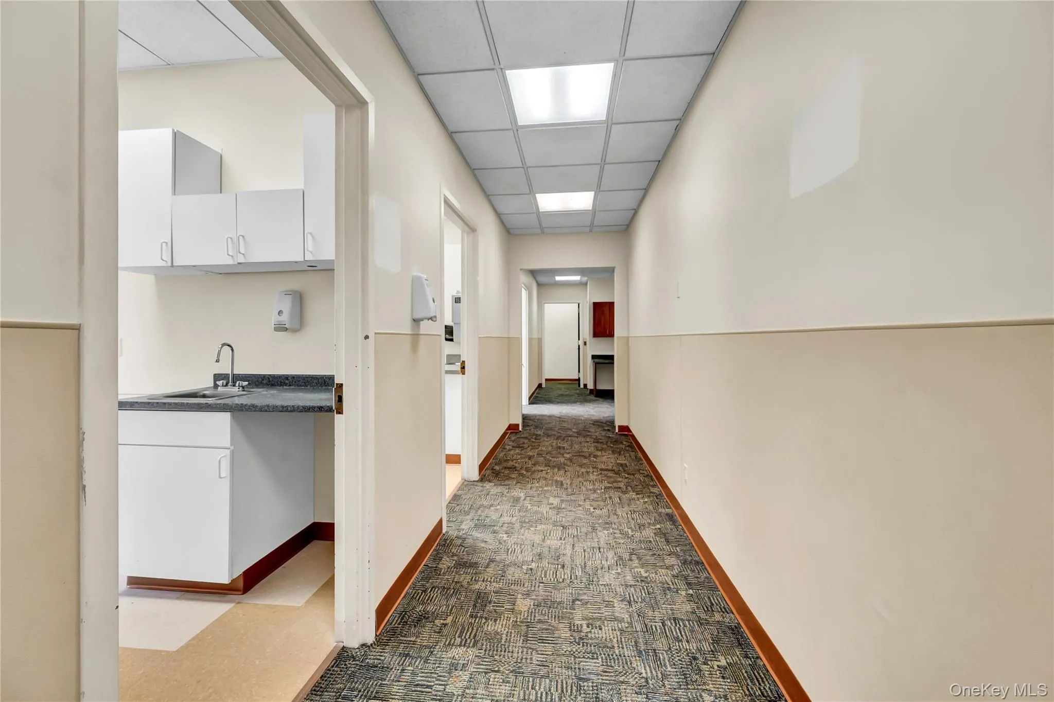 Hall with dark carpet and a drop ceiling Hall with dark carpet and a drop ceiling
