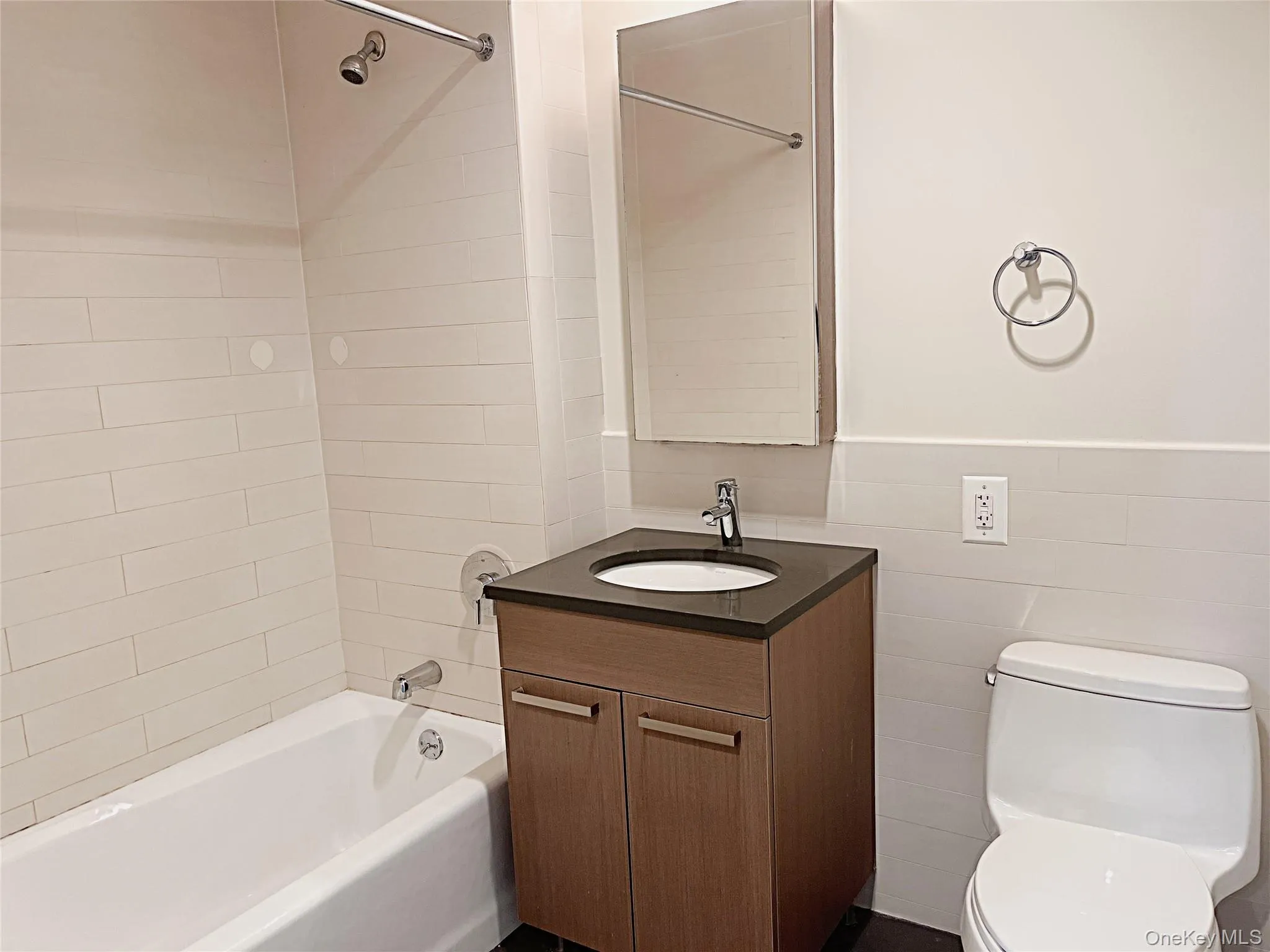 Bathroom featuring vanity, shower / washtub combination, tile walls, and a wainscoted wall Bathroom featuring vanity, shower / washtub combination, tile walls, and a wainscoted wall
