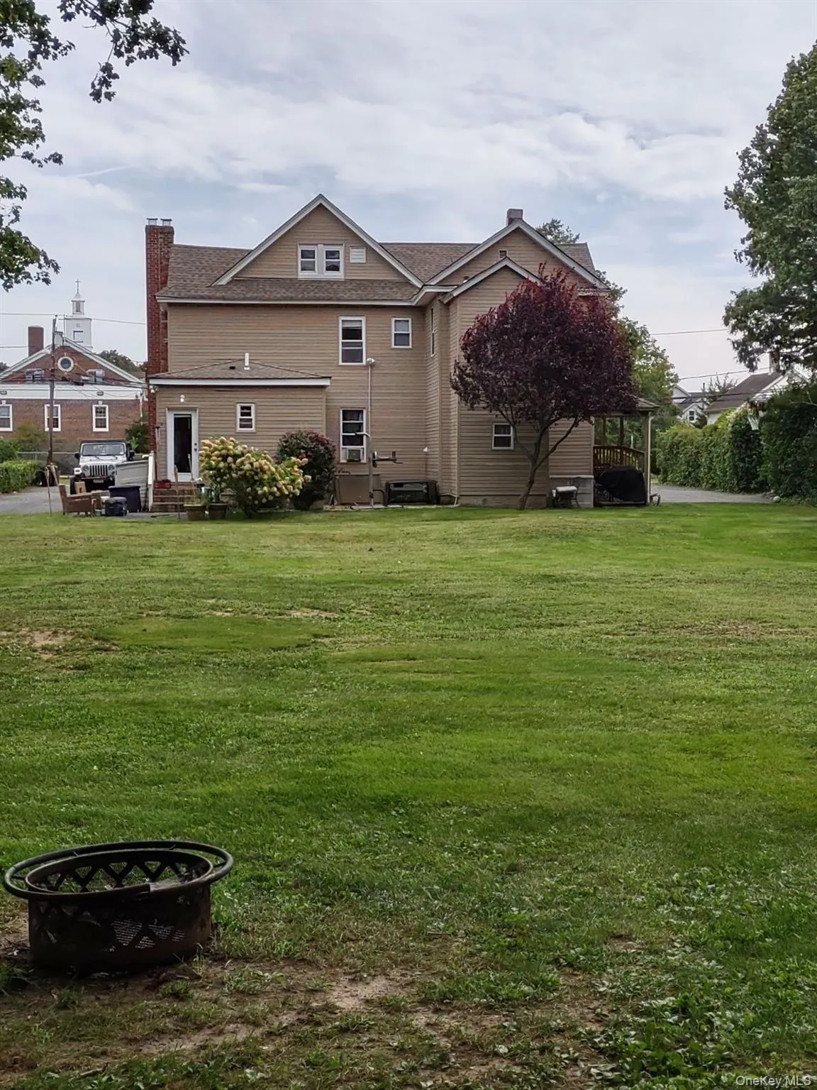 Rear view of house with a chimney, a lawn, and an outdoor fire pit Rear view of house with a chimney, a lawn, and an outdoor fire pit