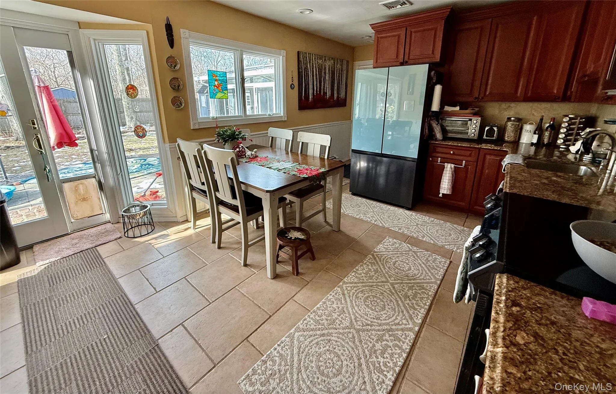 Kitchen featuring dark stone counters, freestanding refrigerator, and light tile patterned floors Kitchen featuring dark stone counters, freestanding refrigerator, and light tile patterned floors