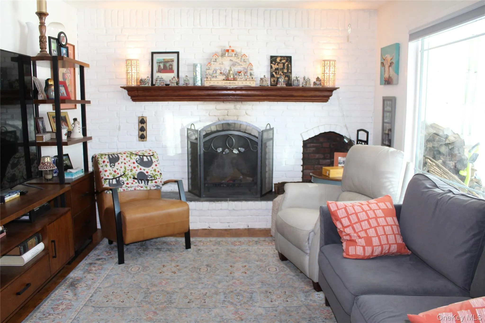 Living area with a fireplace, brick wall, and light wood-type flooring Living area with a fireplace, brick wall, and light wood-type flooring