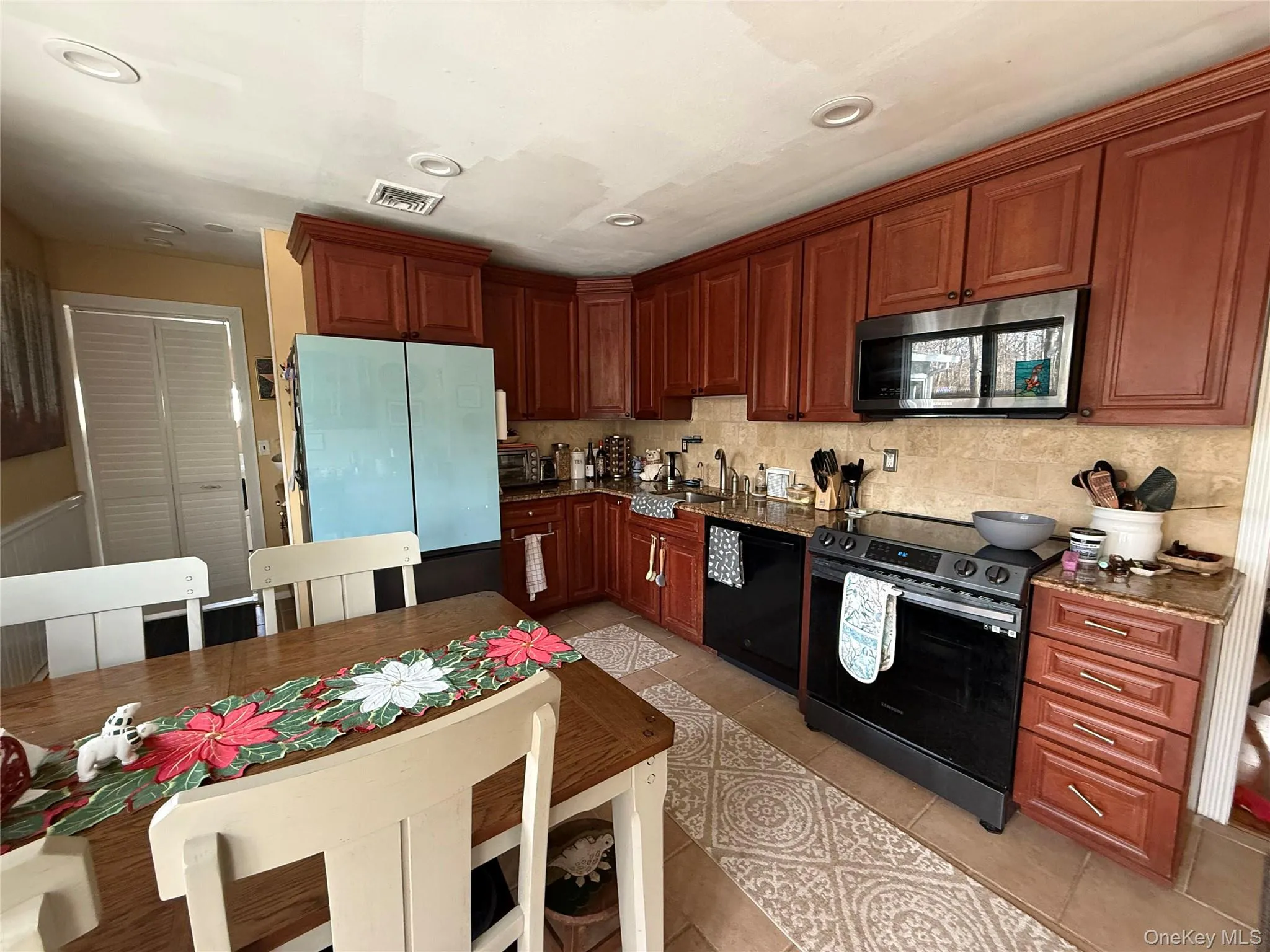 Kitchen with appliances with stainless steel finishes, light tile patterned flooring, tasteful backsplash, dark stone counters, and recessed lighting Kitchen with appliances with stainless steel finishes, light tile patterned flooring, tasteful backsplash, dark stone counters, and recessed lighting