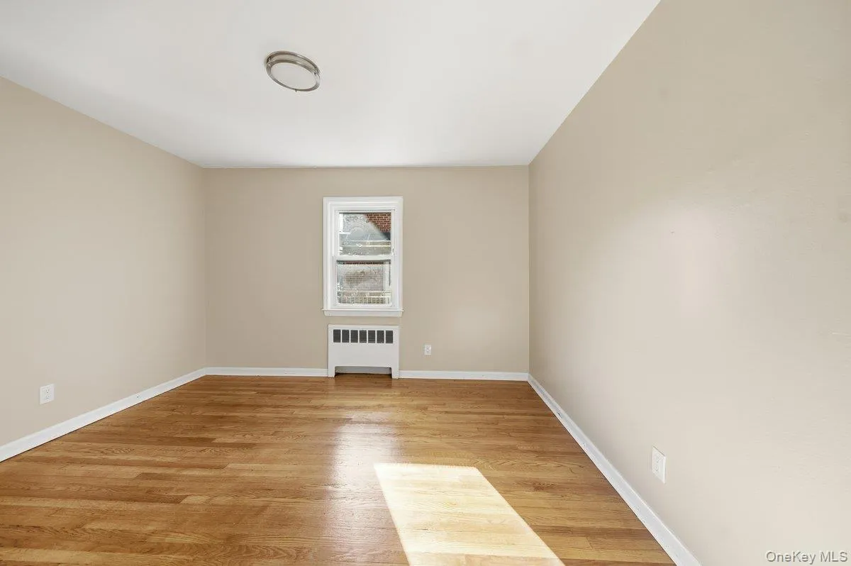 Unfurnished room with light wood-style floors and radiator heating unit Unfurnished room with light wood-style floors and radiator heating unit