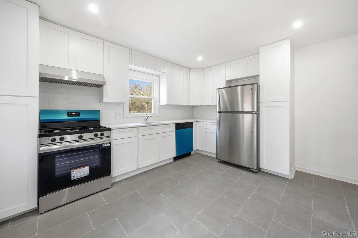 Kitchen featuring appliances with stainless steel finishes, light countertops, white cabinetry, under cabinet range hood, and recessed lighting Kitchen featuring appliances with stainless steel finishes, light countertops, white cabinetry, under cabinet range hood, and recessed lighting