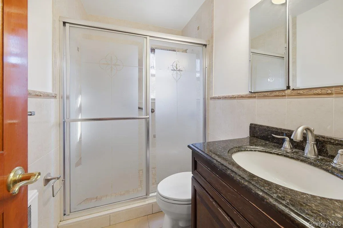 Bathroom featuring vanity, tile walls, and a shower stall Bathroom featuring vanity, tile walls, and a shower stall