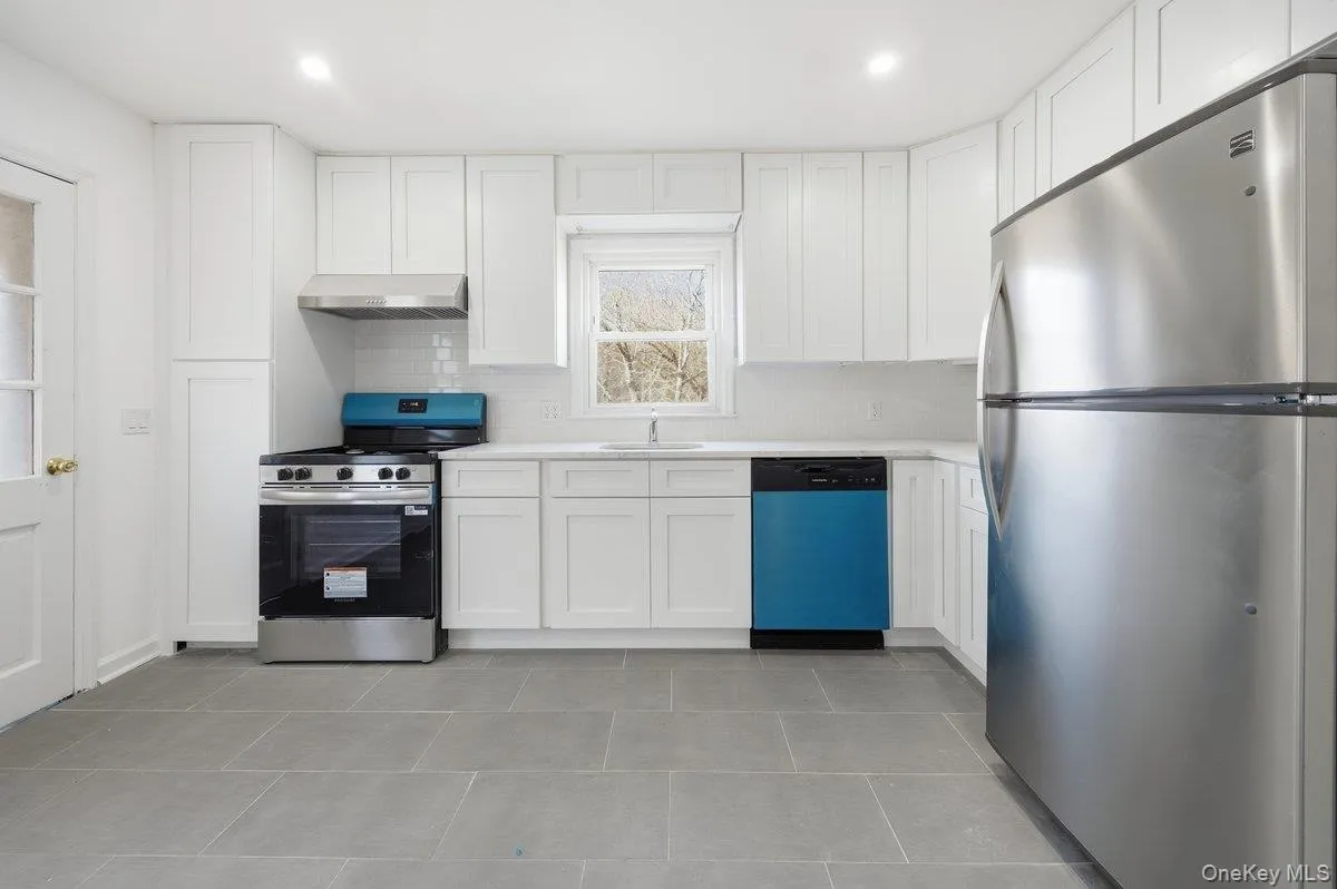Kitchen featuring stainless steel appliances, white cabinets, light countertops, backsplash, and extractor fan Kitchen featuring stainless steel appliances, white cabinets, light countertops, backsplash, and extractor fan